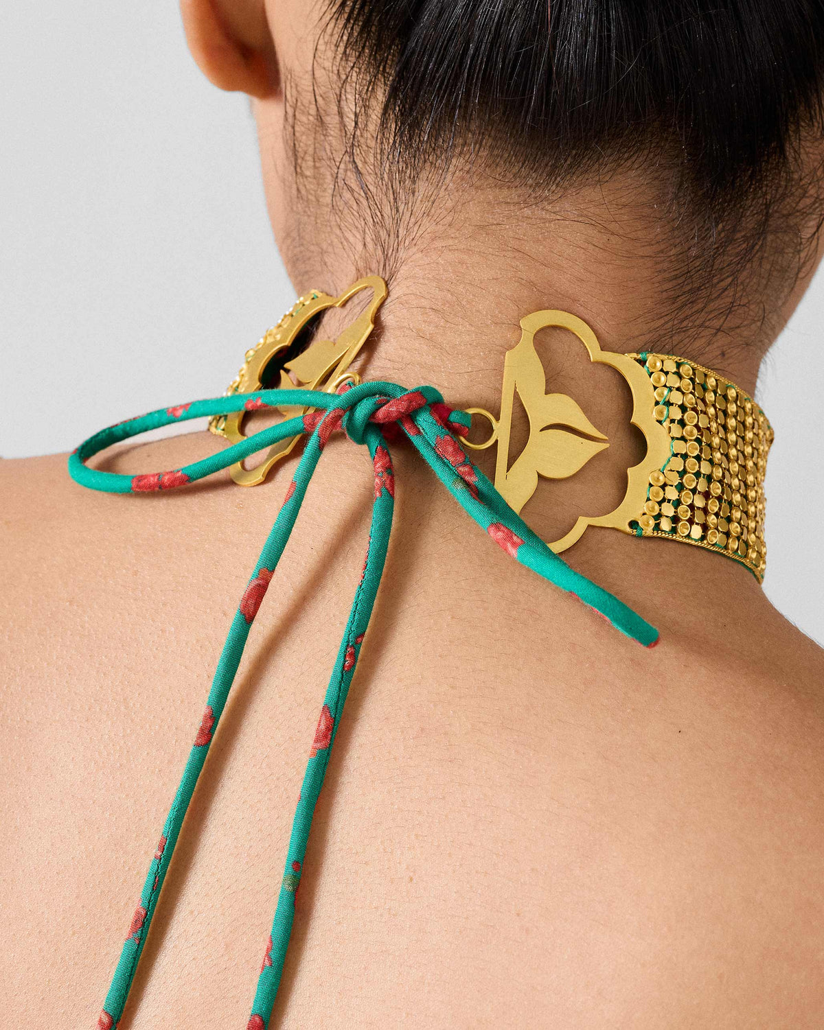 Back of a gold Chain Mail choker showing scalloped plates and fabric ties.