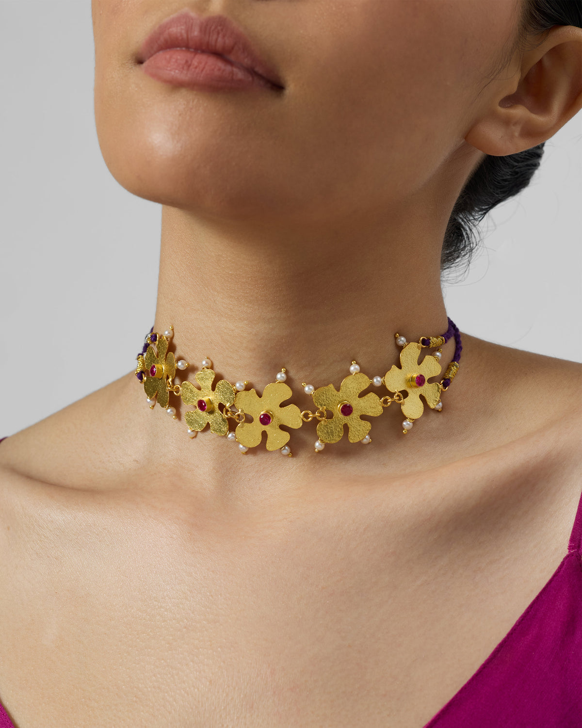 Gold phool haar necklace with red stone flowers worn as a choker.
