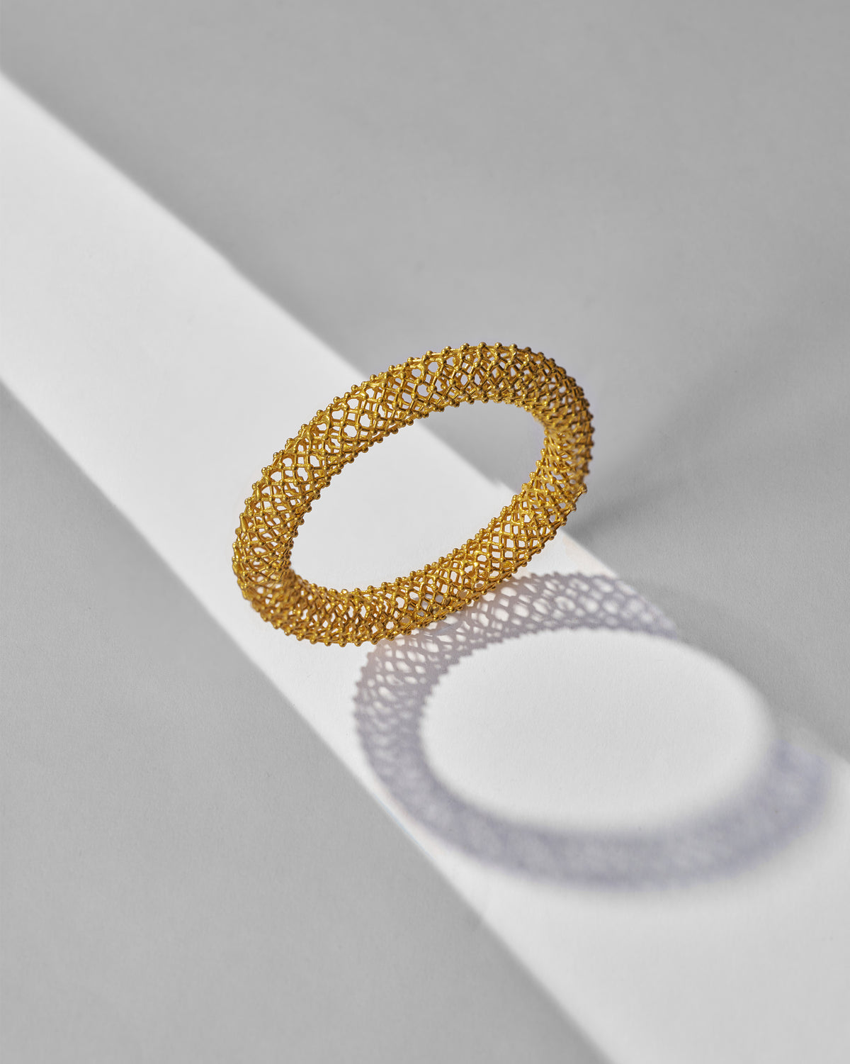 Gold mesh Infinity bangle showing its hollow lattice tube.