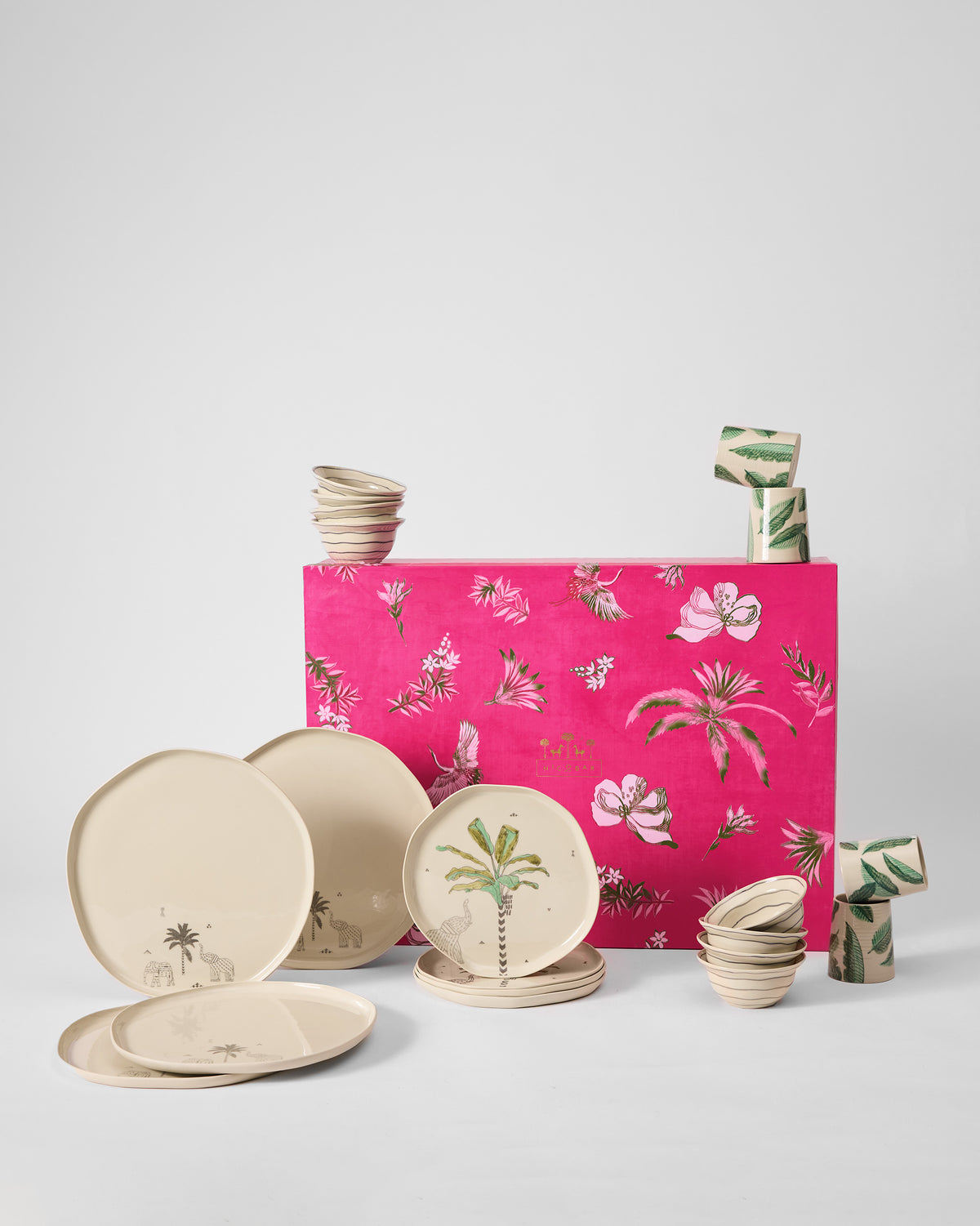 Ceylon Trail Dinner Gift Set in front of its pink gift box, with palm-print plates and bowls.
