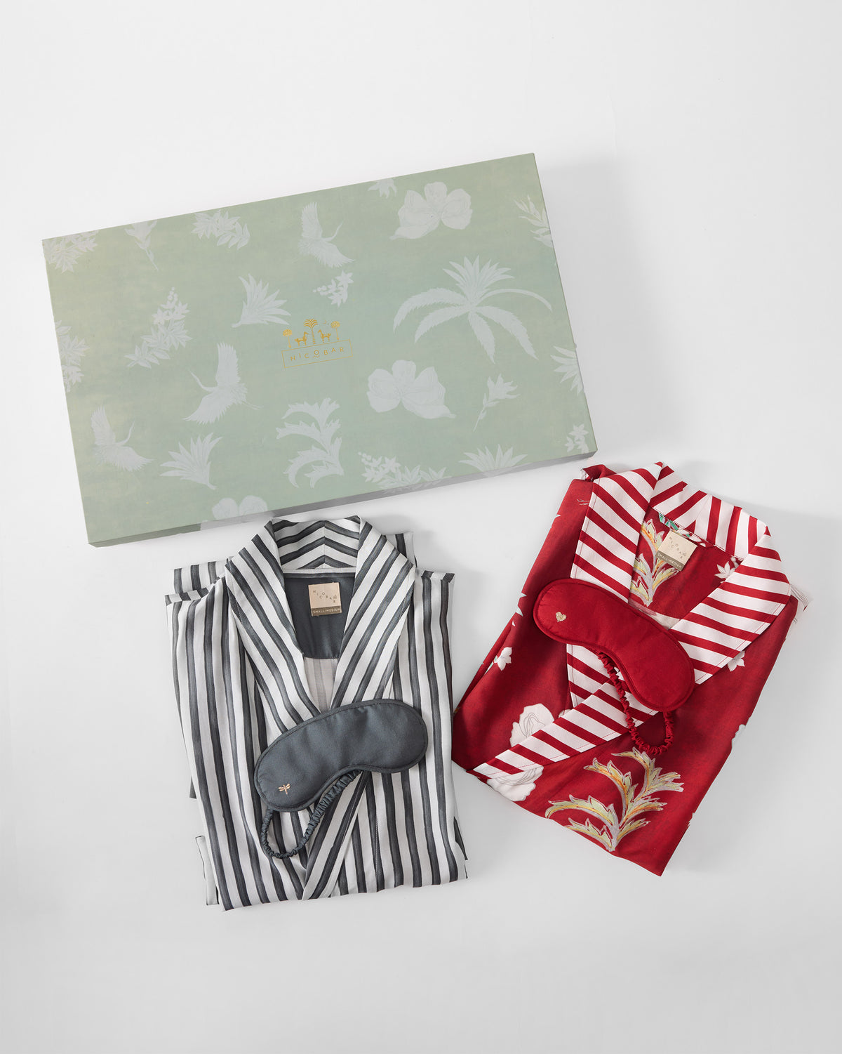 Folded Reverie robes and sleep masks laid below the sage gift box.