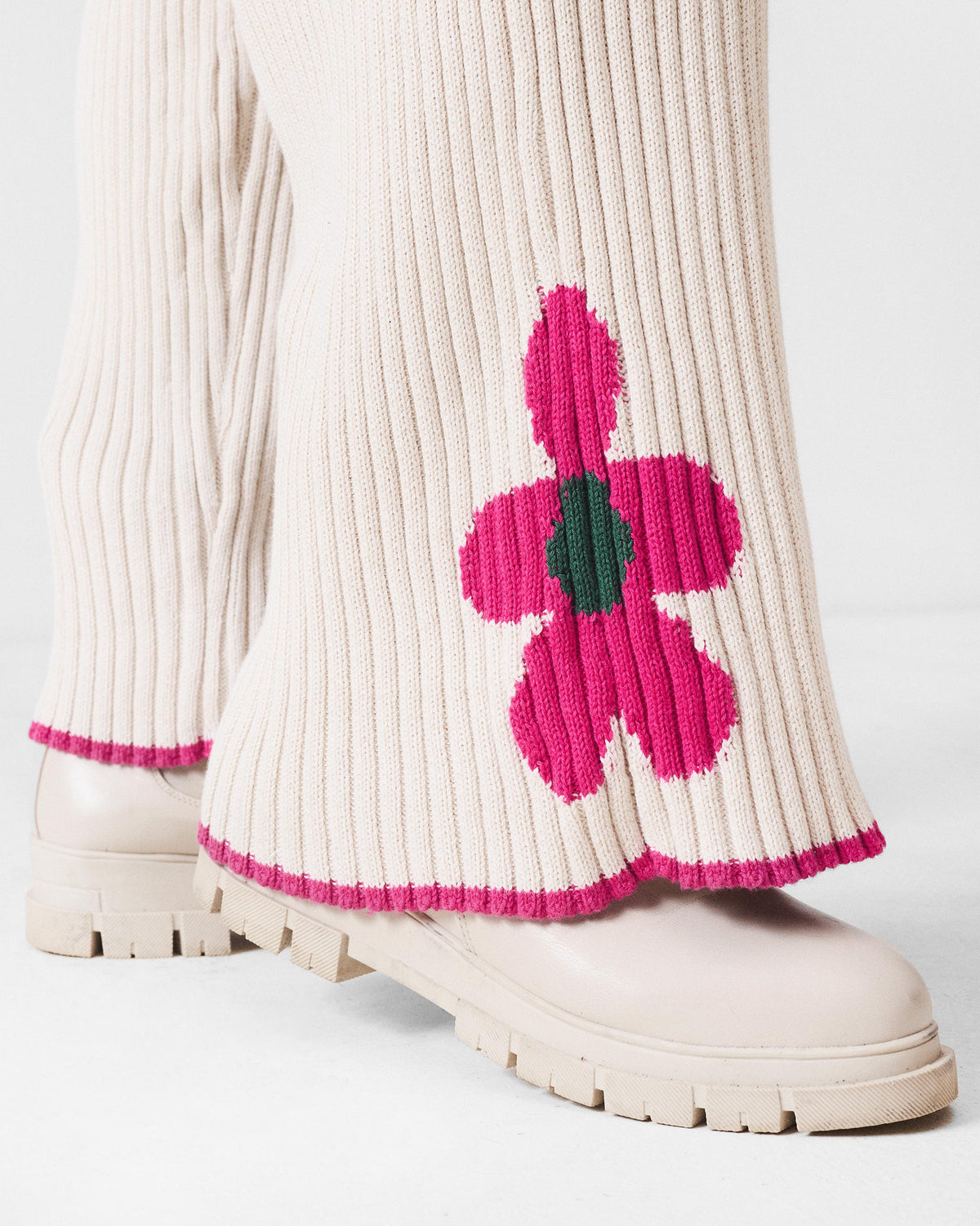 Close-up of a pink flower on ivory rib knit trousers.