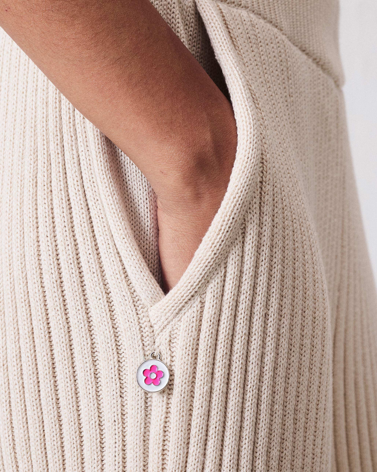 Close-up of a pink flower charm on ivory rib knit trousers.