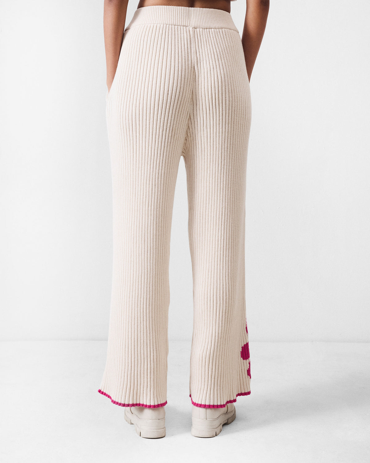 Back of ivory rib knit trousers with pink tip hems.