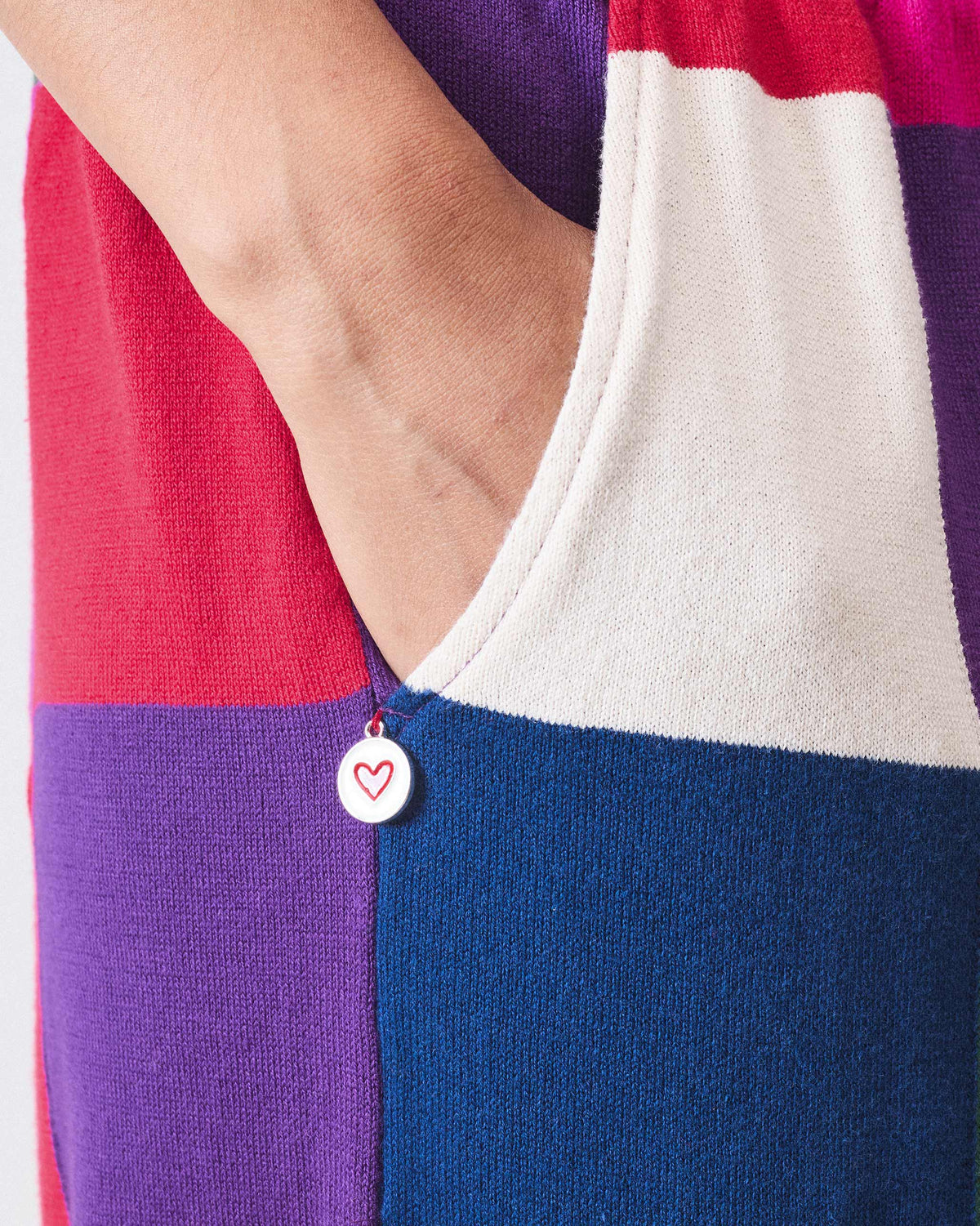 Close-up of a red heart charm on a multicolour knit trousers pocket.