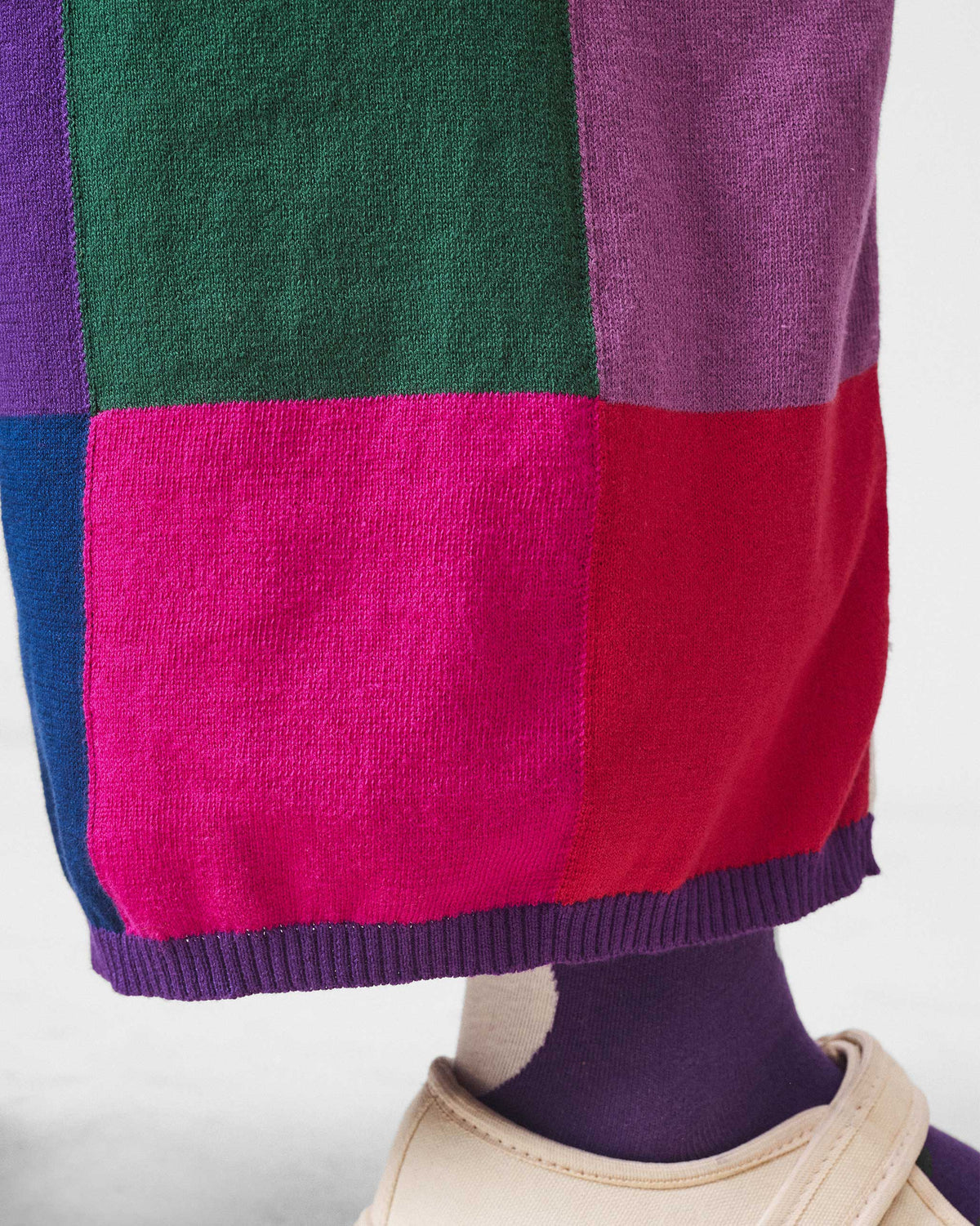 Close-up of a purple ribbed hem on multicolour check knit trousers.