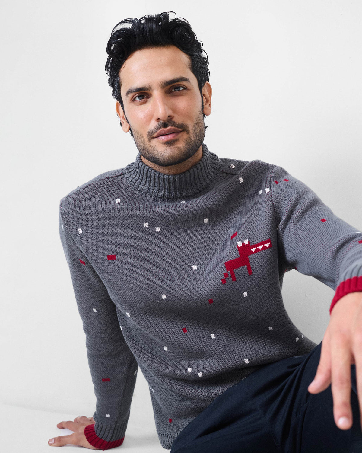 Person wearing a charcoal Crew Neck sweater with a red pixel dino motif.