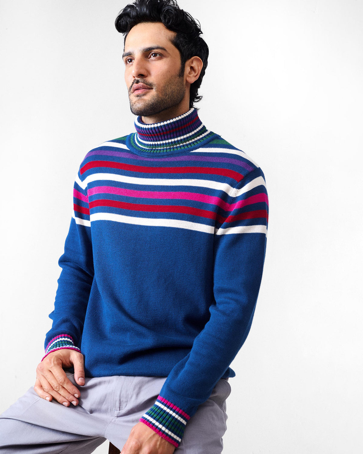 Person wearing a navy Ringer sweater with multicolour stripes across the chest.