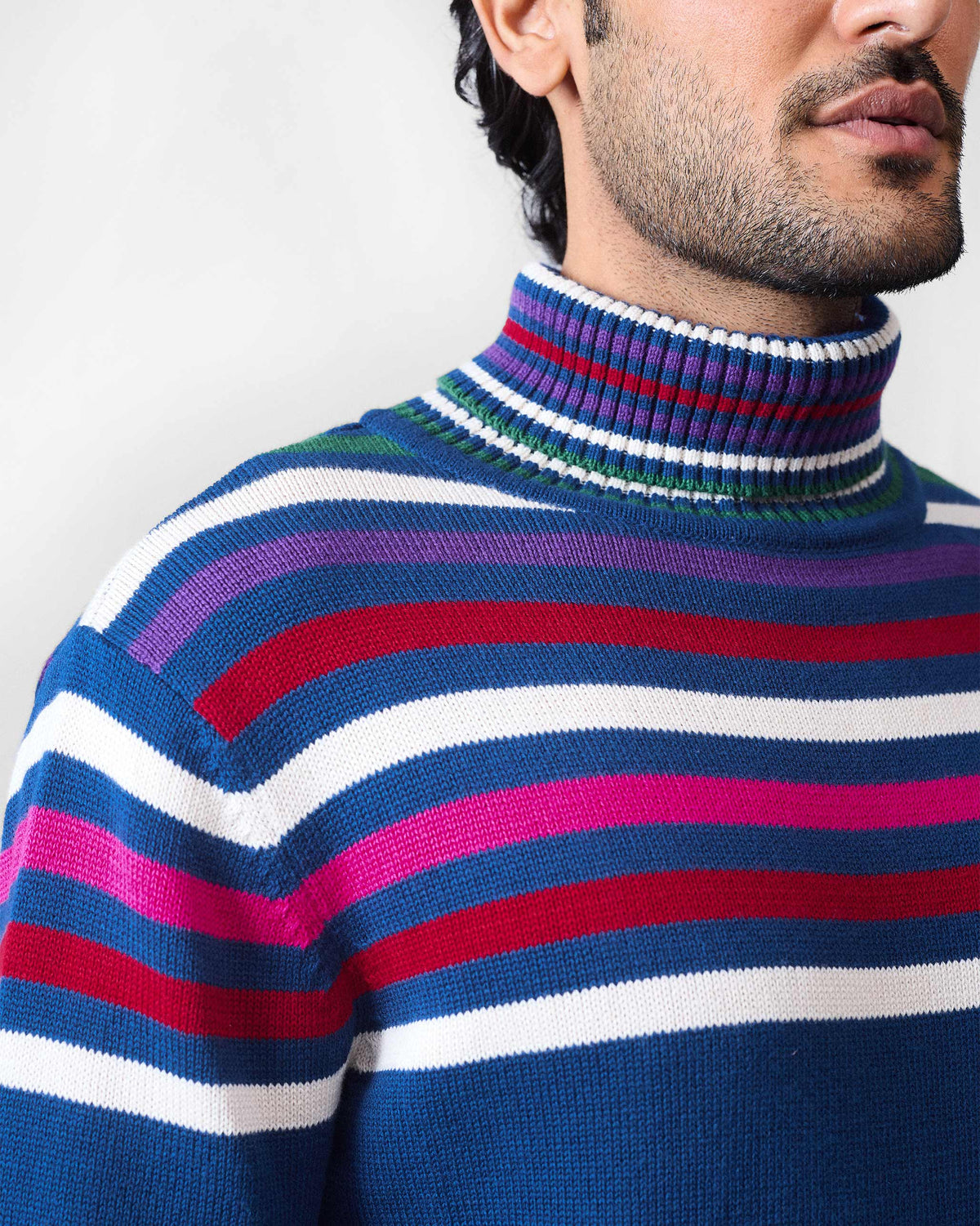 Close-up of multicolour stripes on the chest of a navy Ringer sweater.