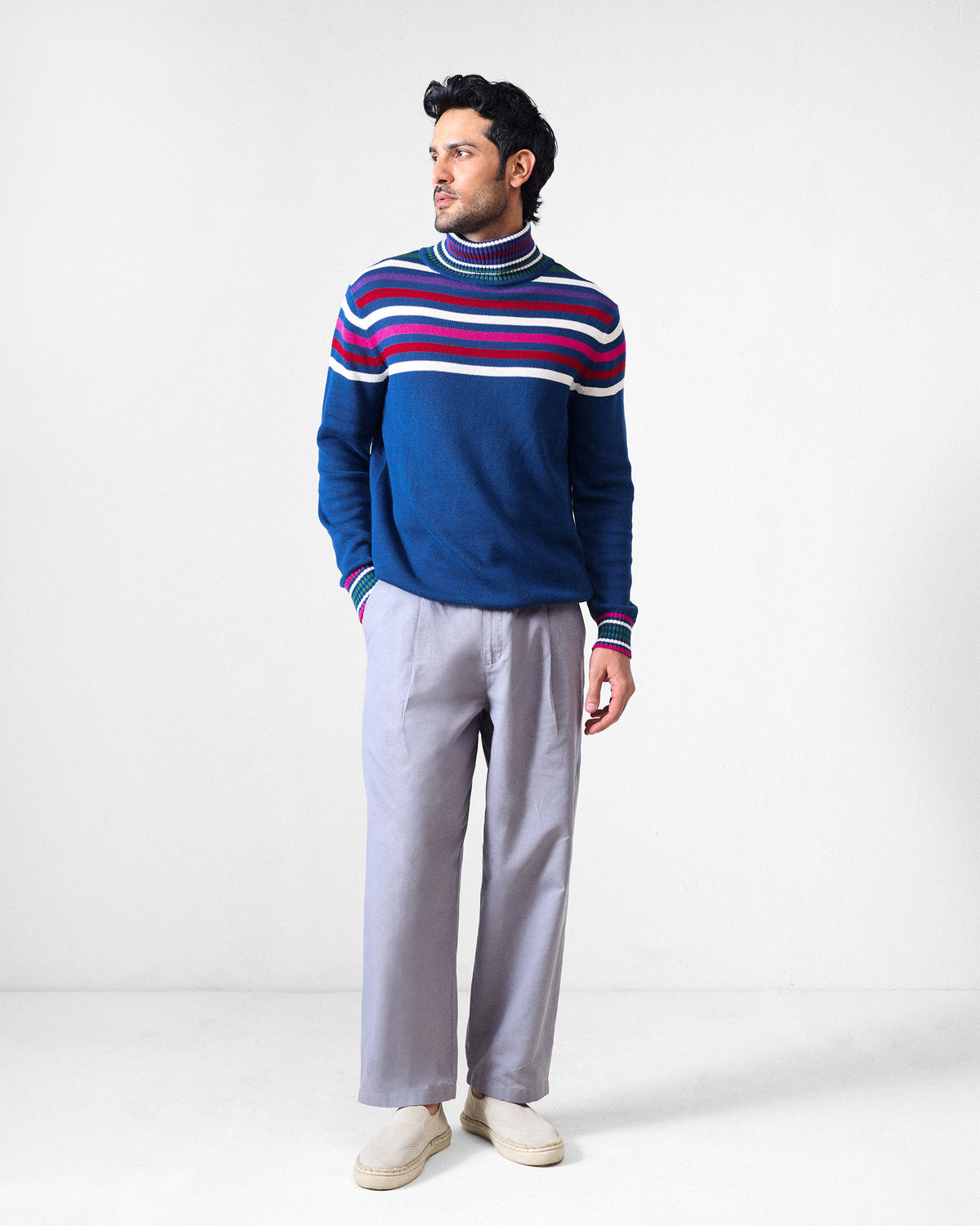 Person wearing a navy Ringer sweater with multicolour stripes and a turtleneck.