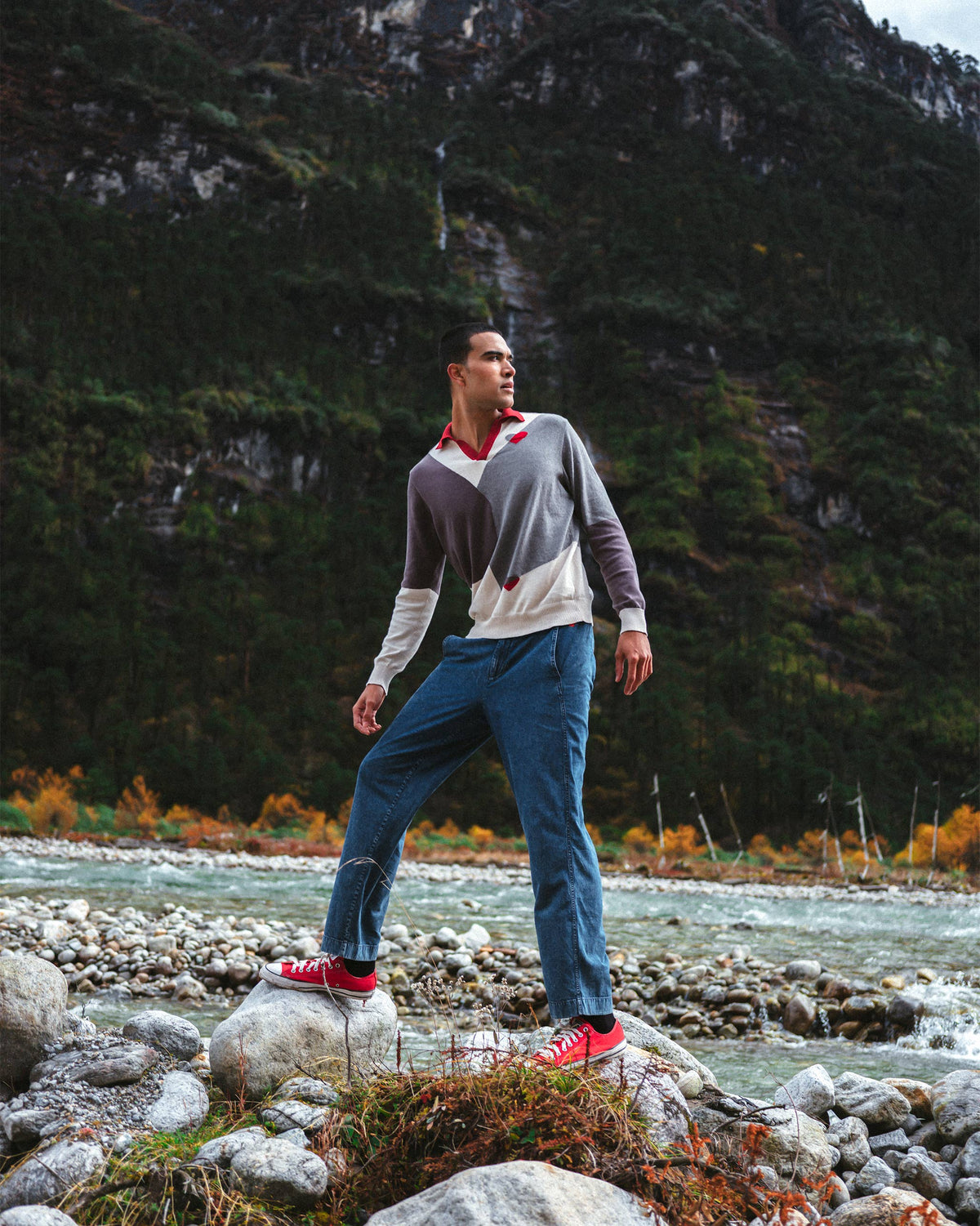 Person wearing a grey Dom Sweater with cream colour blocks and a red collar.