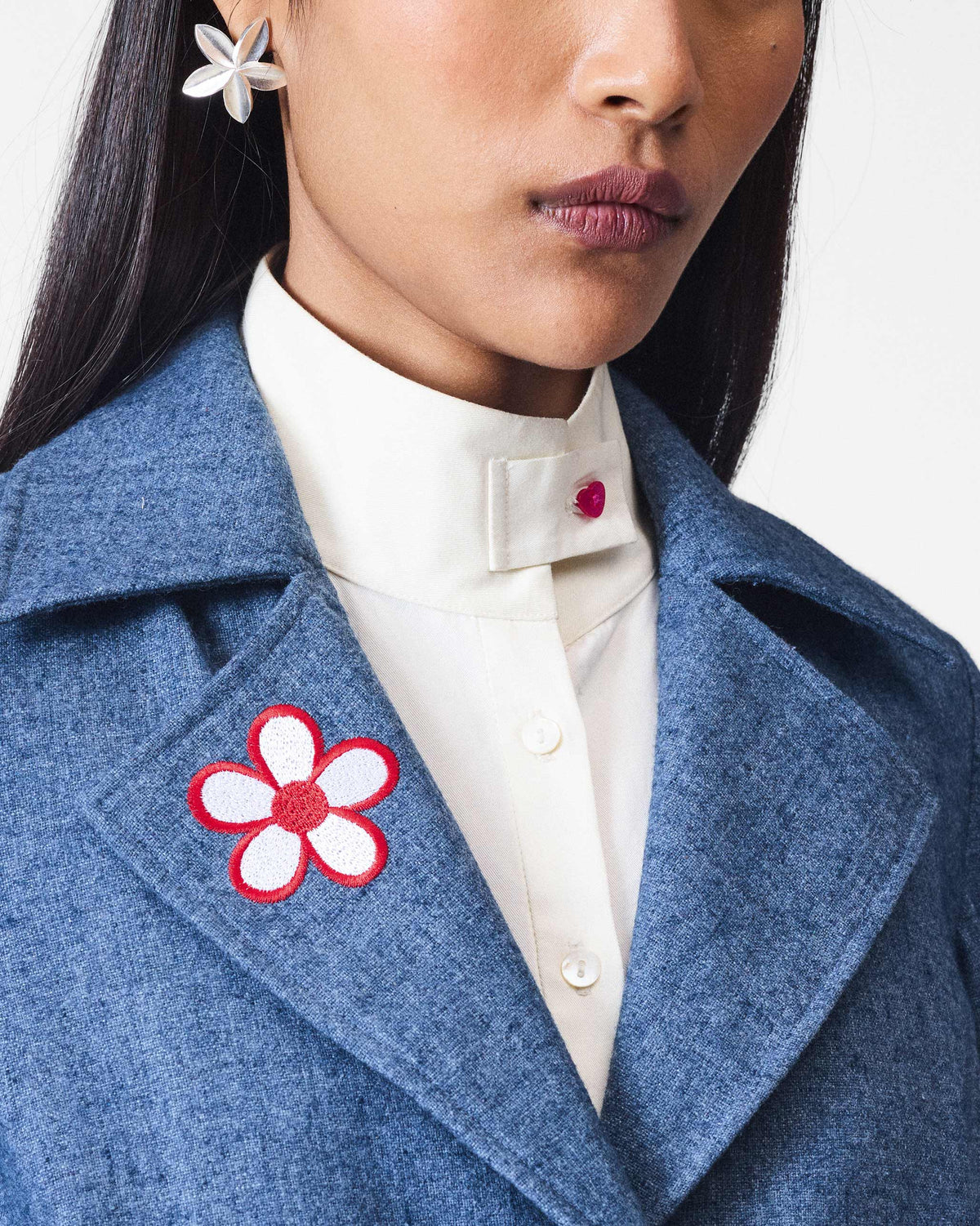 Close-up of a dust blue Trace Jacket showing the flower lapel patch.