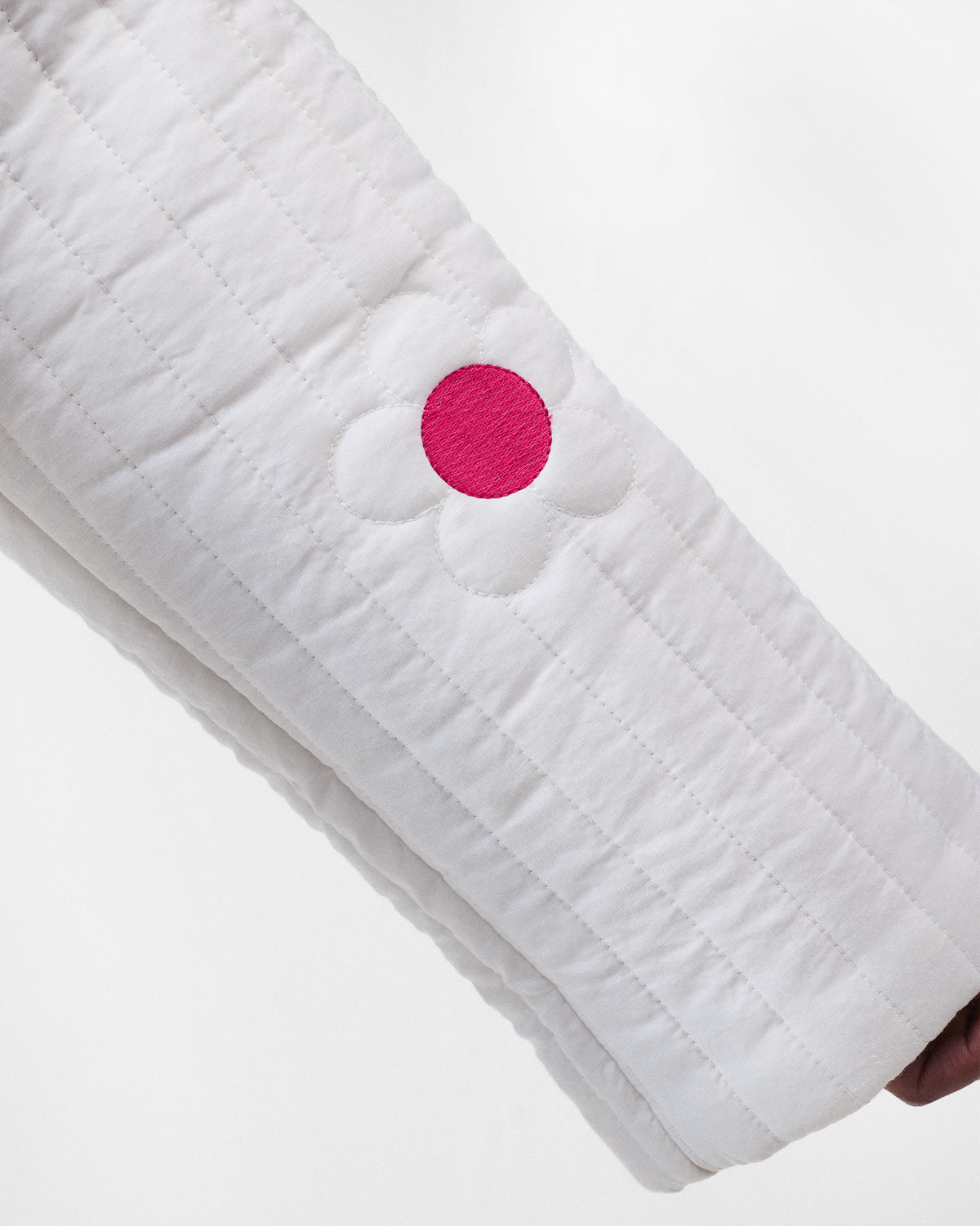 Close-up of a quilted flower with a fuchsia embroidered centre on the Botanik jacket.