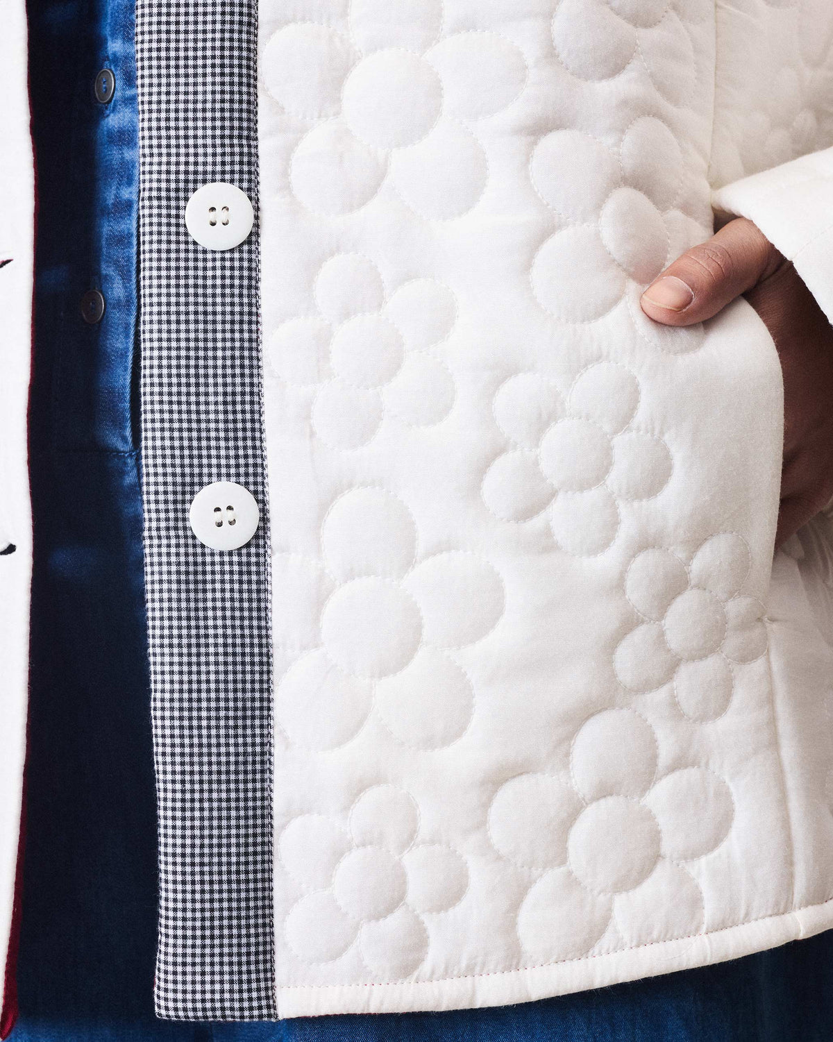 Close-up of flower quilting and a gingham button placket on the ivory Botanik jacket.
