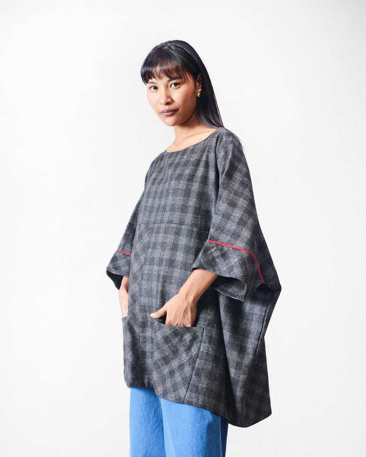 Fable Top worn at an angle in black and charcoal check with red sleeve lines.