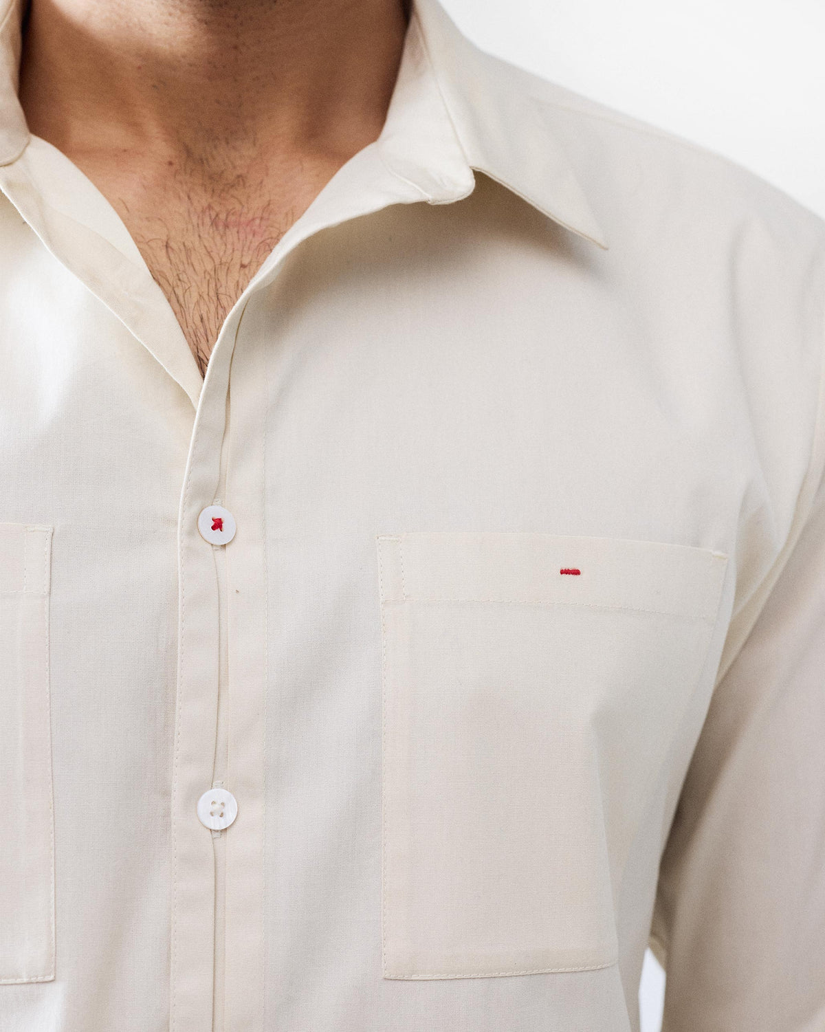Ivory Abe shirt chest pockets with red bar-tack stitching.