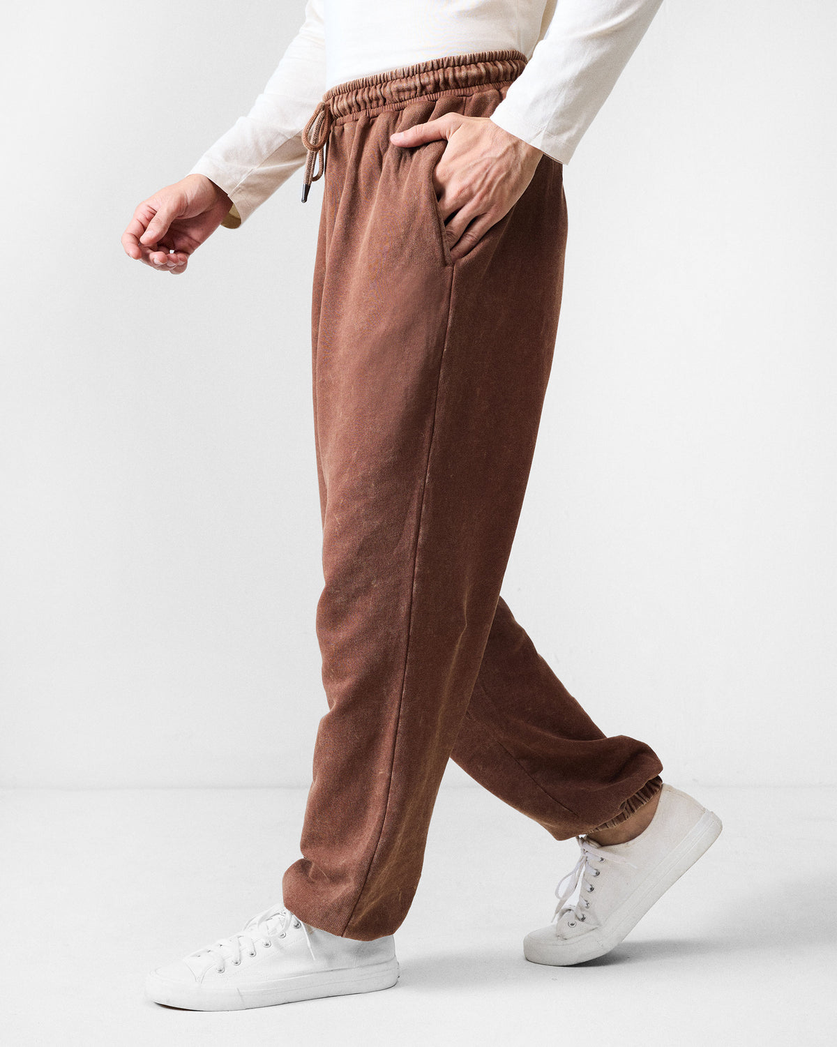 Side view of brown Drift bottoms with a relaxed baggy fit.