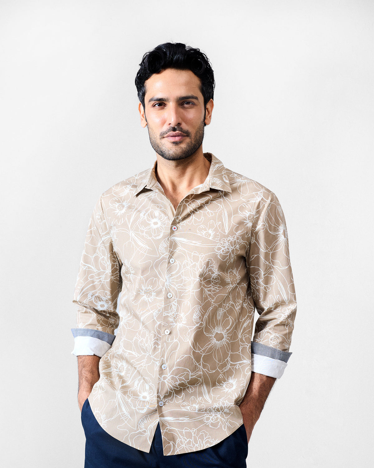 Person wearing a light brown Hakuna Shirt with a white floral print.