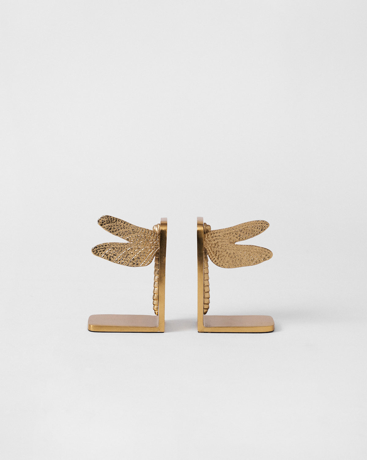 Front view of gold dragonfly bookends with outstretched textured wings.