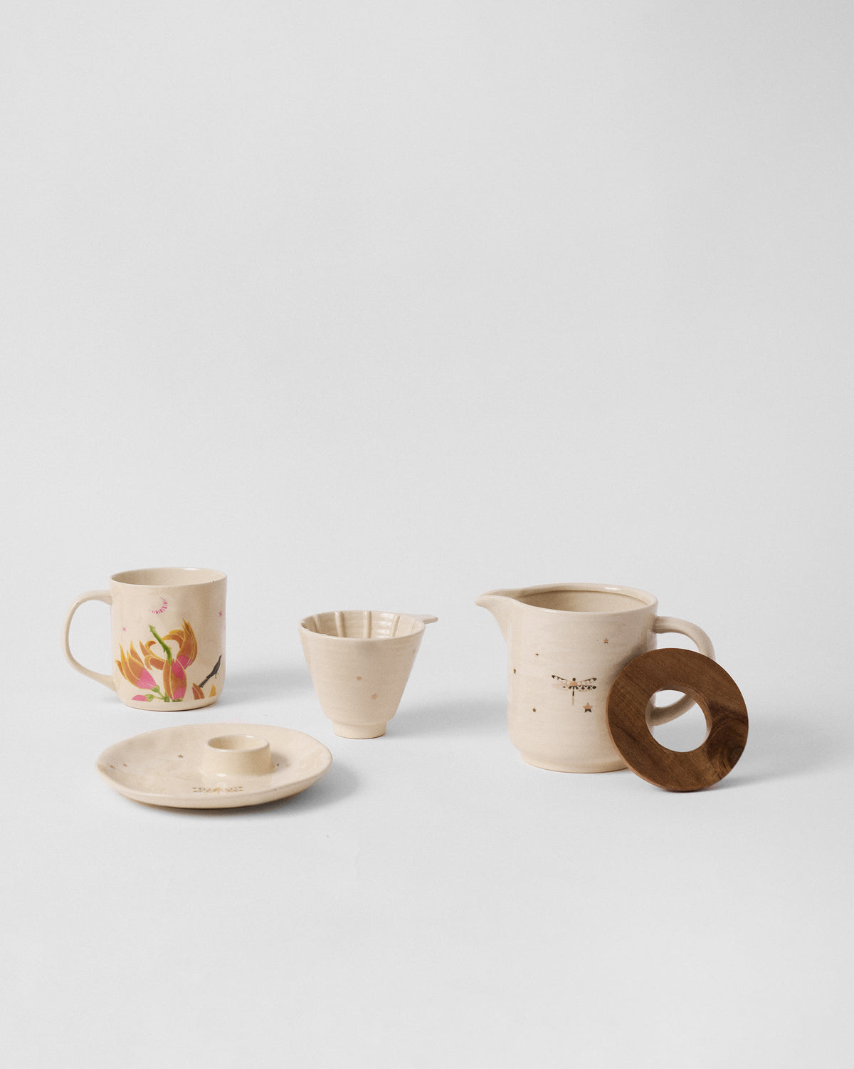 Aaranya ceramic pieces including floral mug, dragonfly pitcher, dripper and wooden ring.