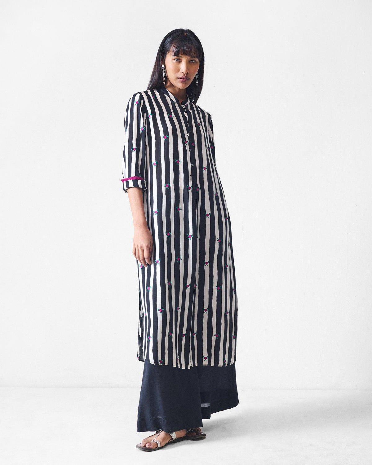 Person wearing a black and beige striped long kurta with pink embroidery.
