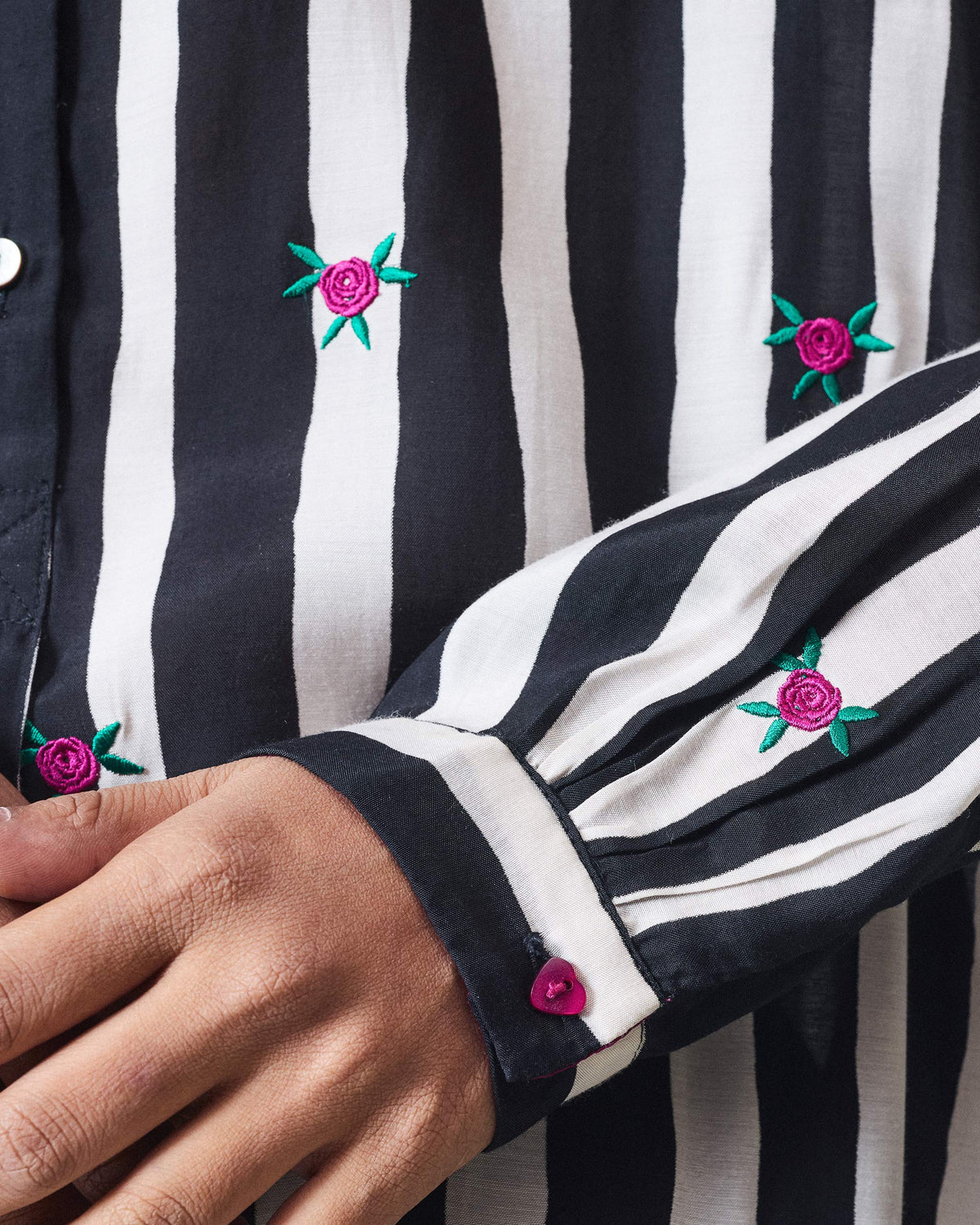 Close-up of pink rose embroidery on a black and beige striped long kurta.