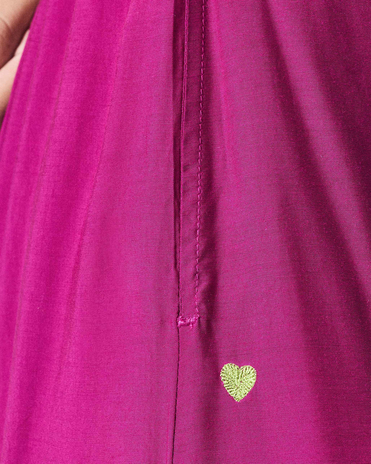Close-up of green heart embroidery on mulberry Uneven Hem pants.