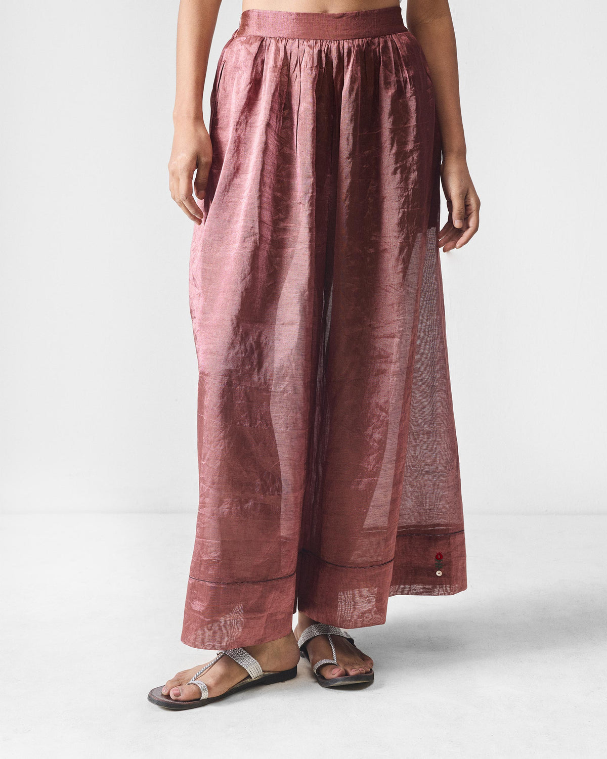 Person wearing metallic pink Charisma pants with a gathered waist and wide legs.