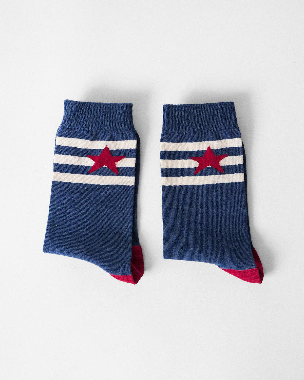 Pair of navy Starbed Socks with white cuff stripes and a red star.