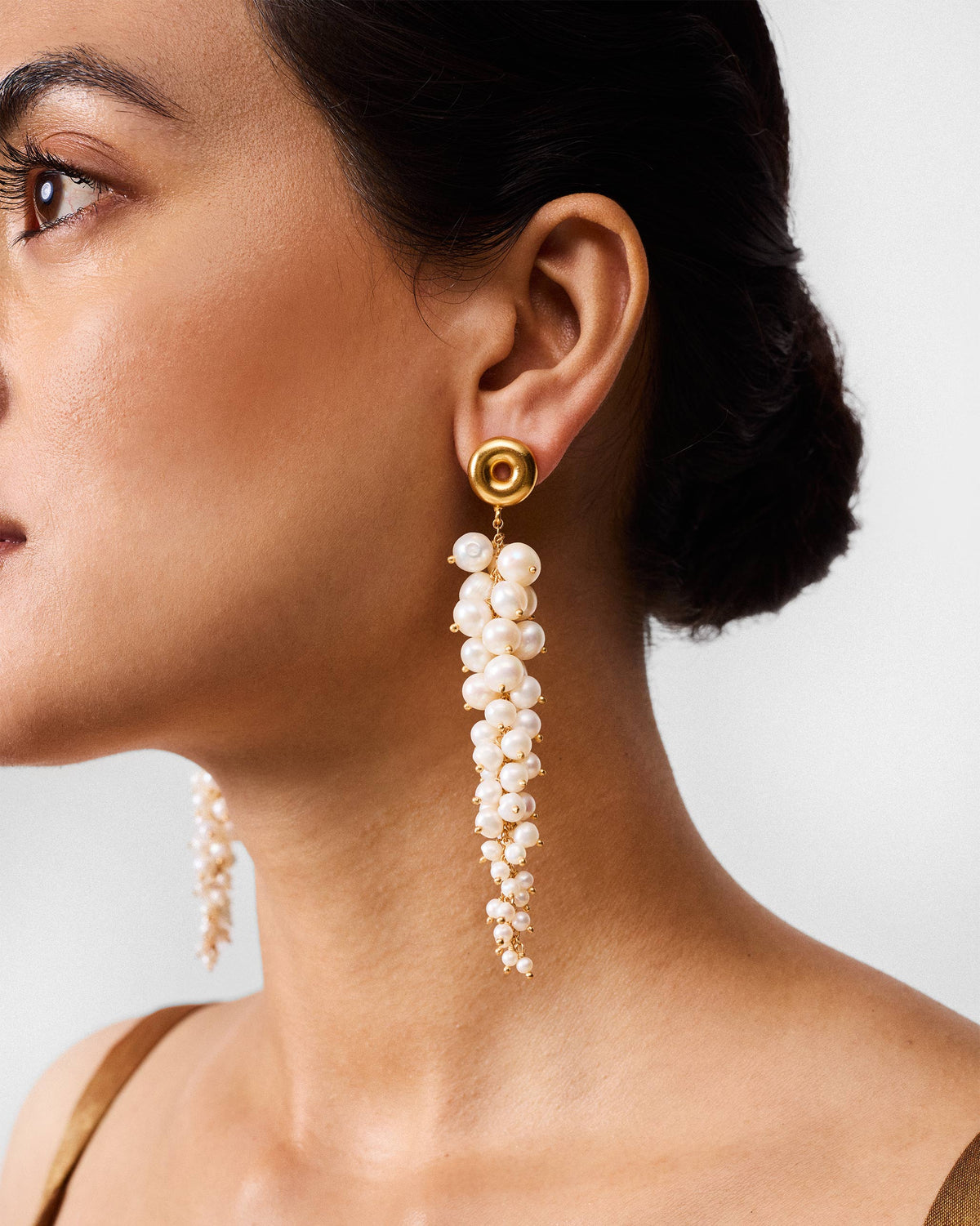 Side profile of a gold Mogra shoulder duster with a pearl cluster on a person.