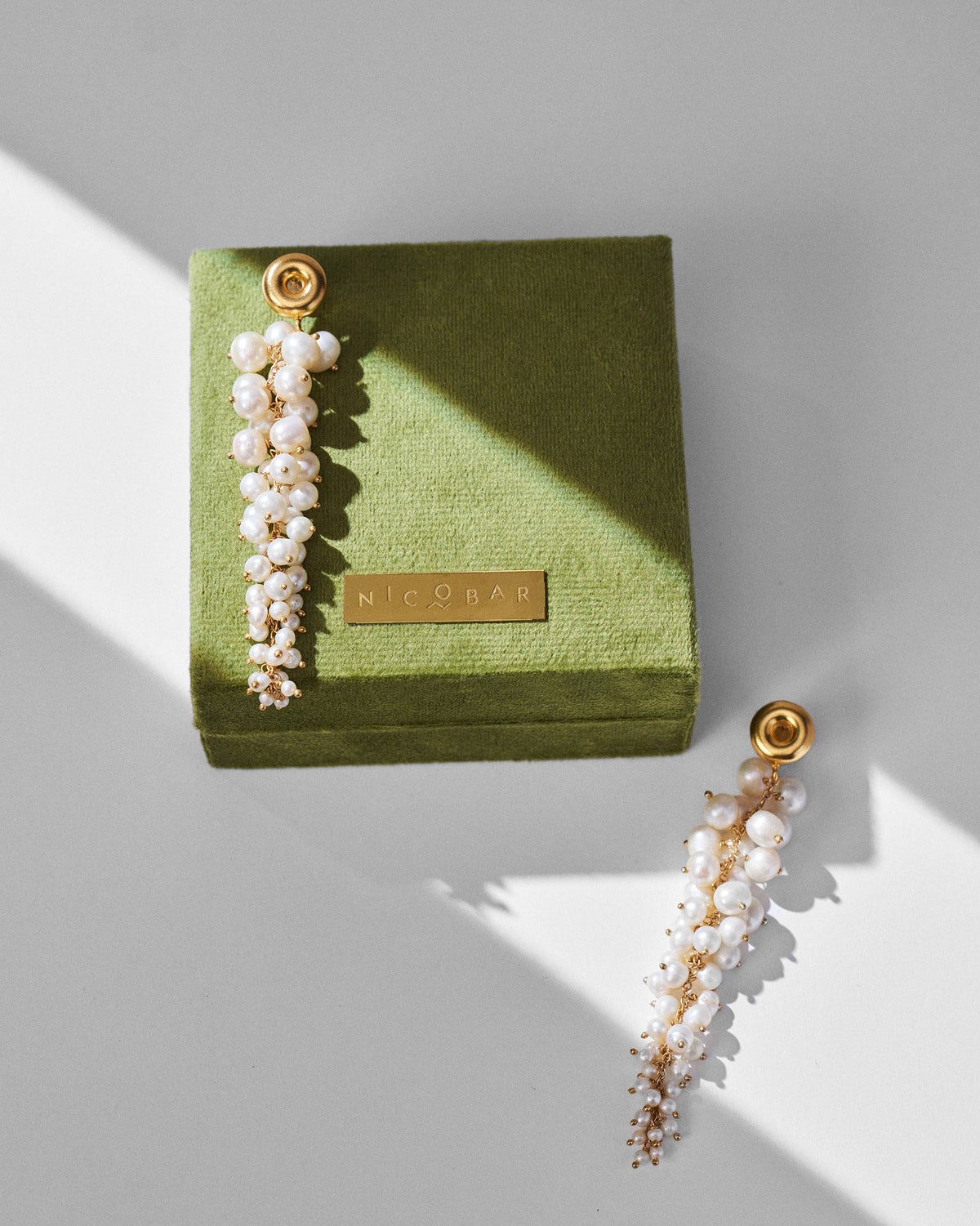 Gold Mogra shoulder dusters with pearl clusters on a green Nicobar gift box.