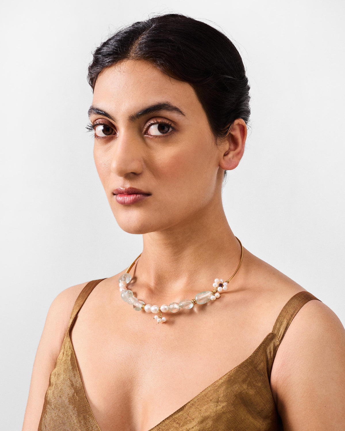 Person wearing a Noorani gold wire collar with stones and pearls.