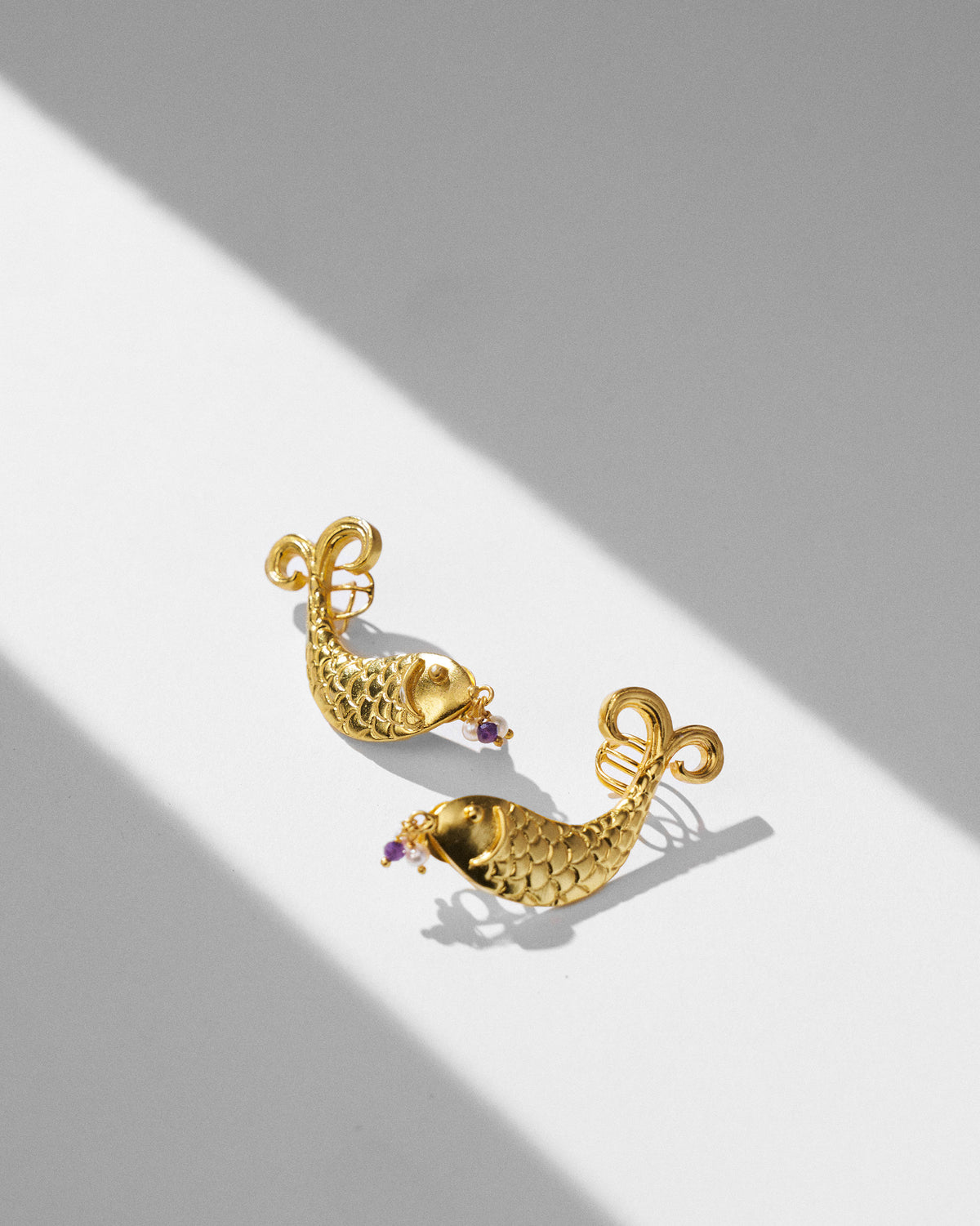 Pair of gold Dupki fish studs with scale texture and bead drops.
