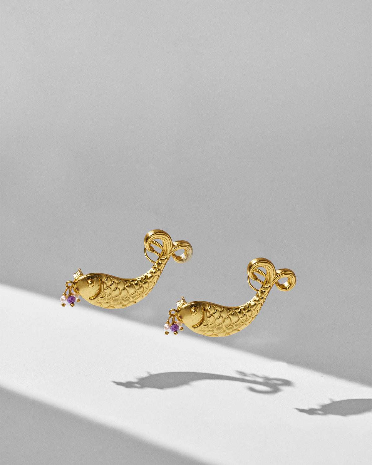 Gold Dupki fish studs showing curved scaled bodies and scroll tails.
