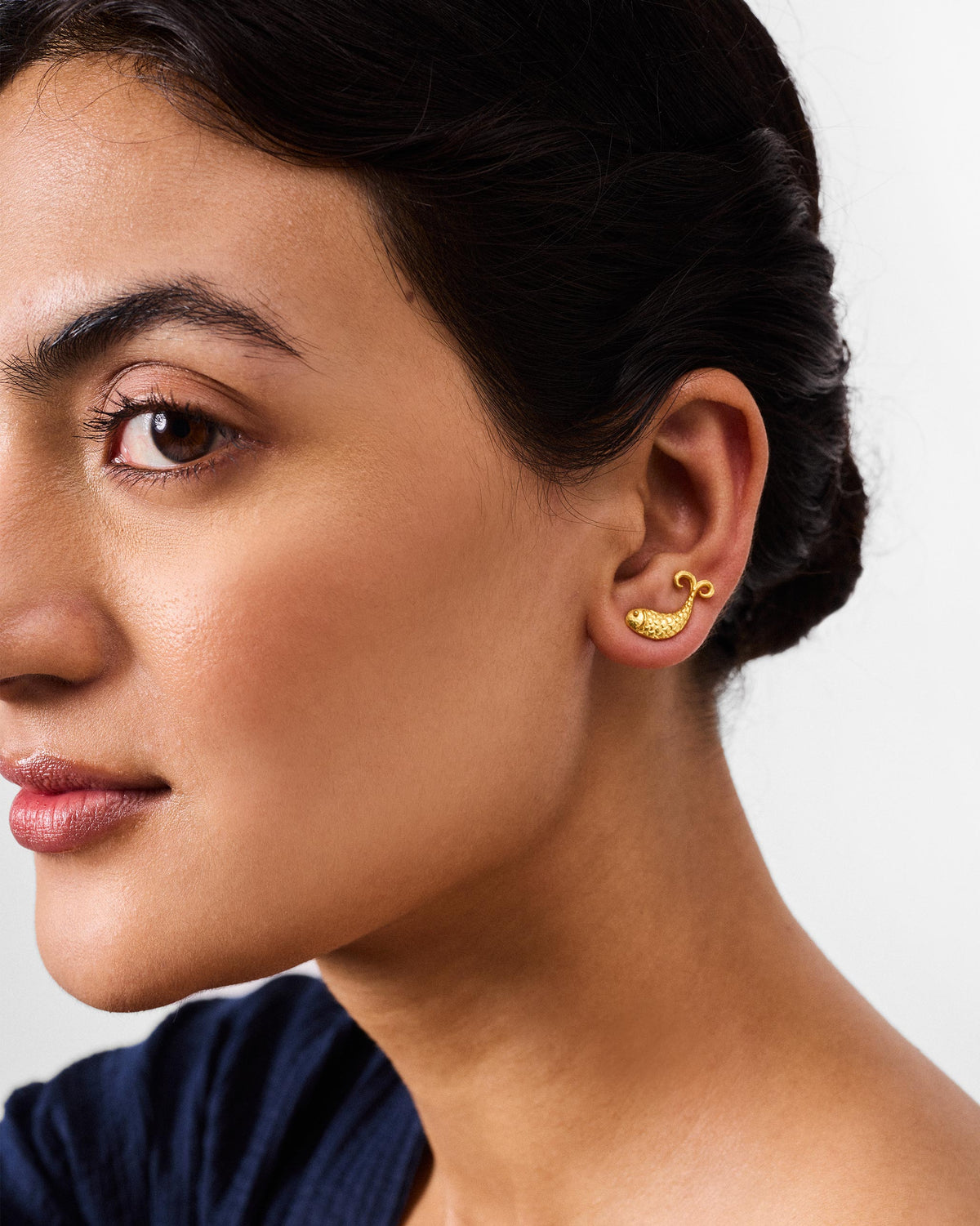 Gold fish Jalpari stud on an earlobe.