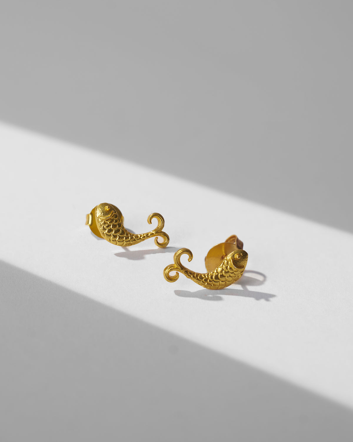 Pair of gold fish Jalpari studs laid flat.