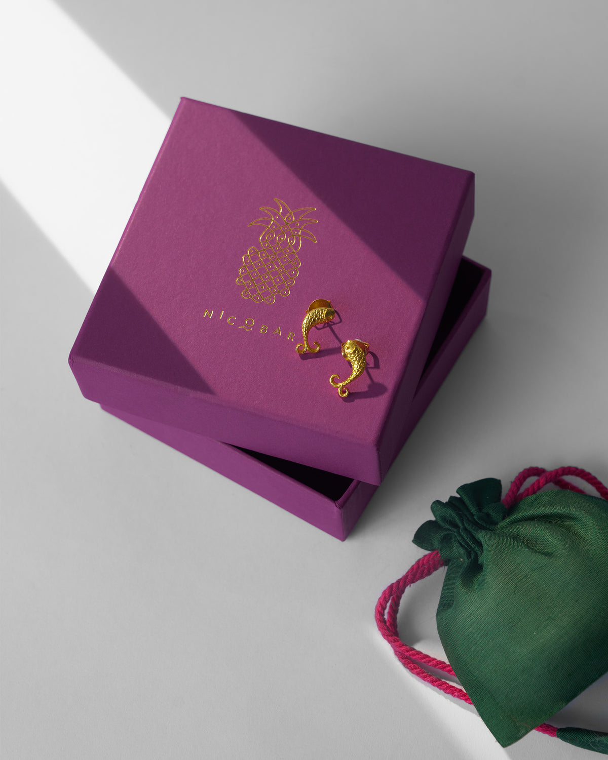 Gold fish Jalpari studs on a purple Nicobar gift box.