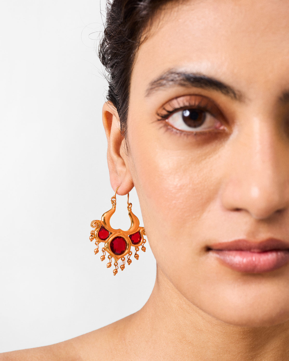 Side profile of antique gold Darbaar Balis with red glass stones on a person.