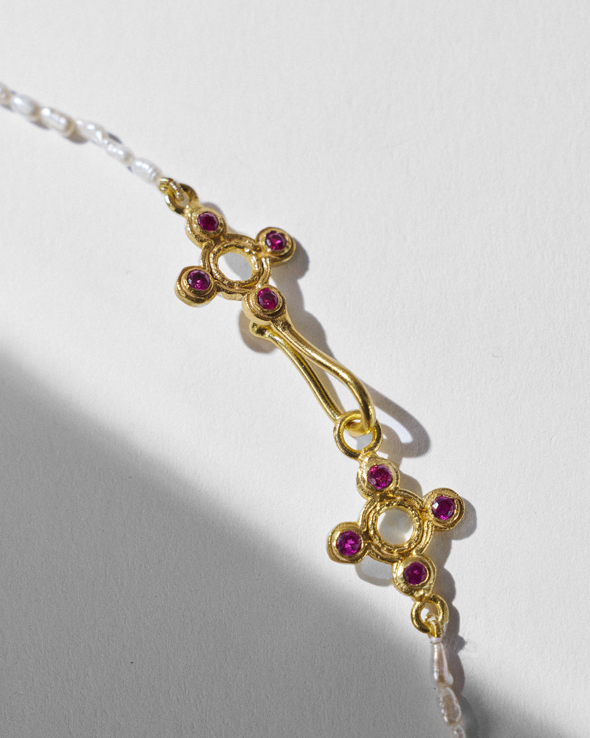 Close-up of Bindu choker gold clasp with red stone cross motifs.