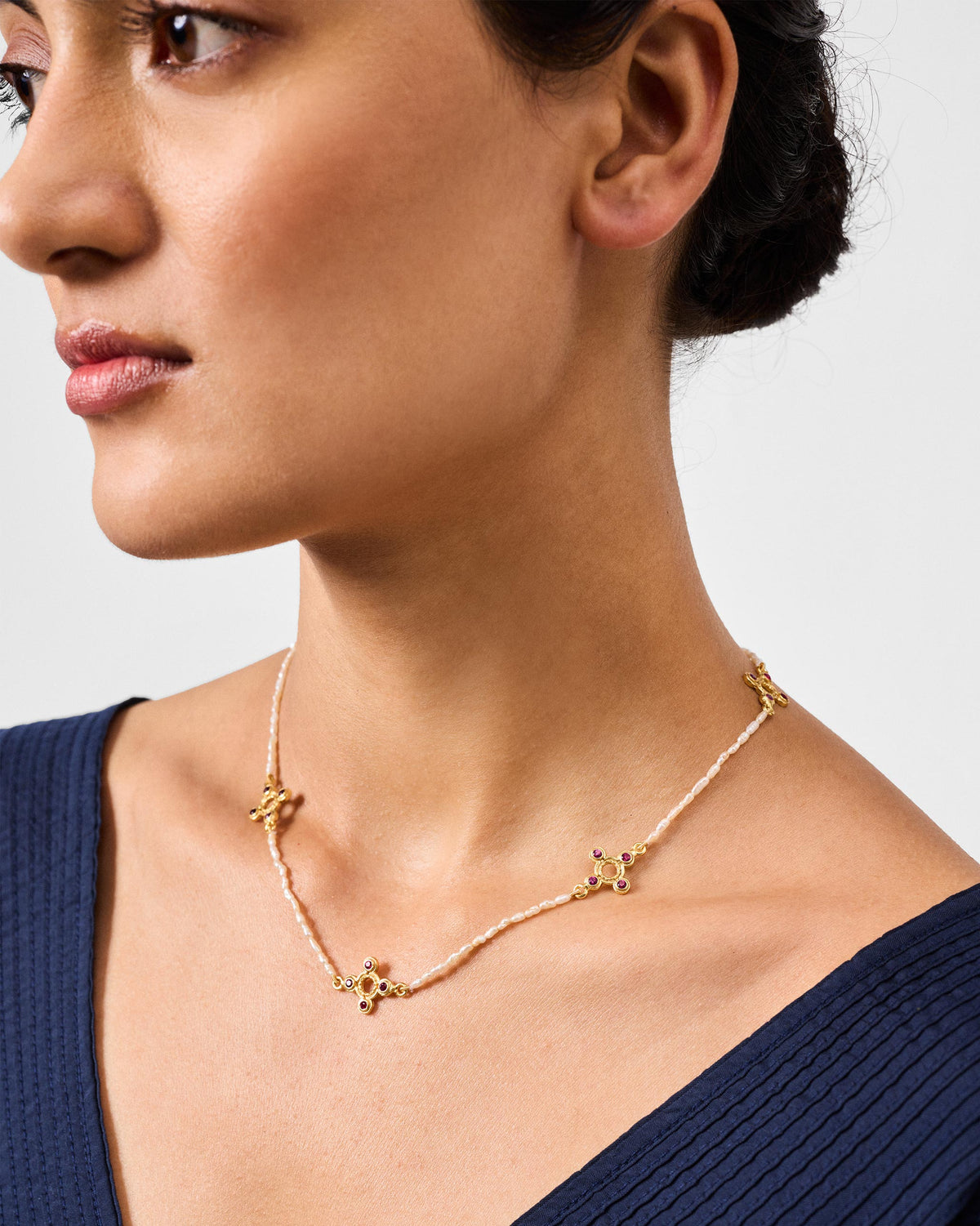 Person wearing a gold Bindu pearl choker with red stone motifs.