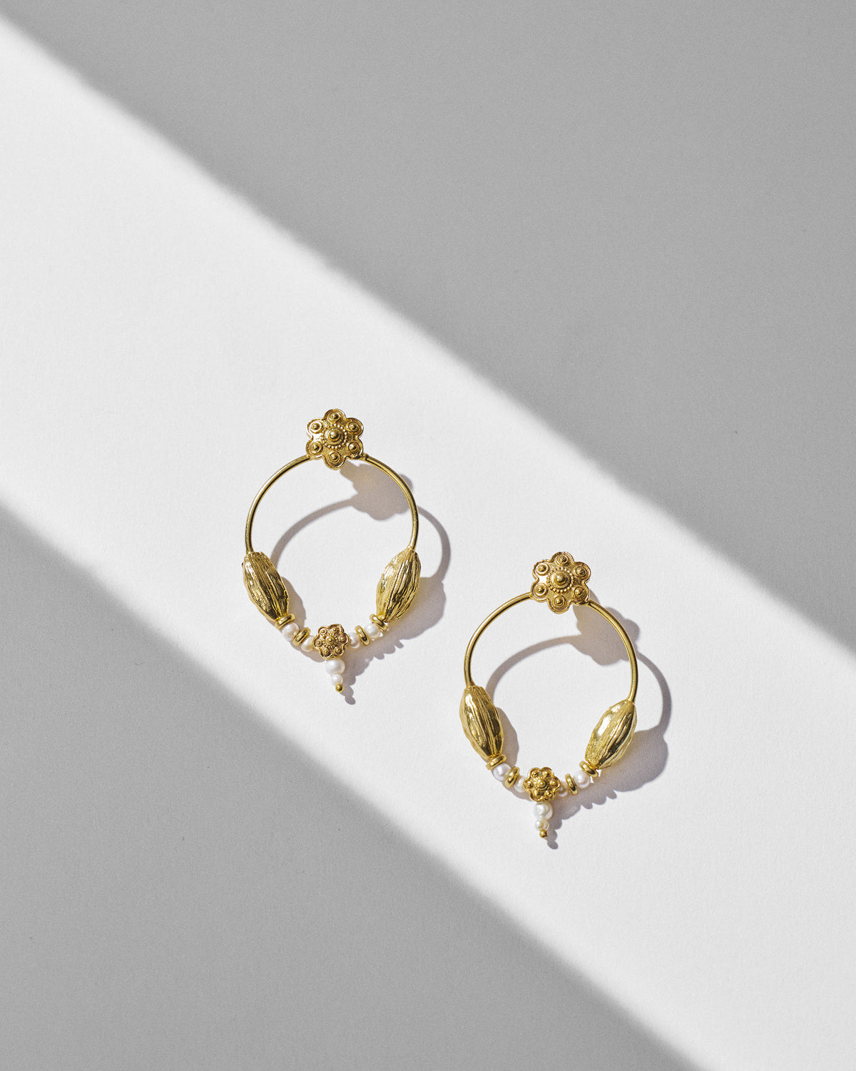 Pair of gold Kumud hoops with flower motifs, pod beads and pearl drops.
