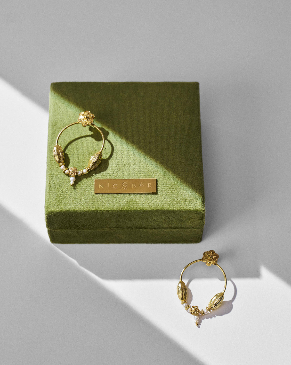 Gold Kumud hoops with pearl accents on an olive green Nicobar gift box.