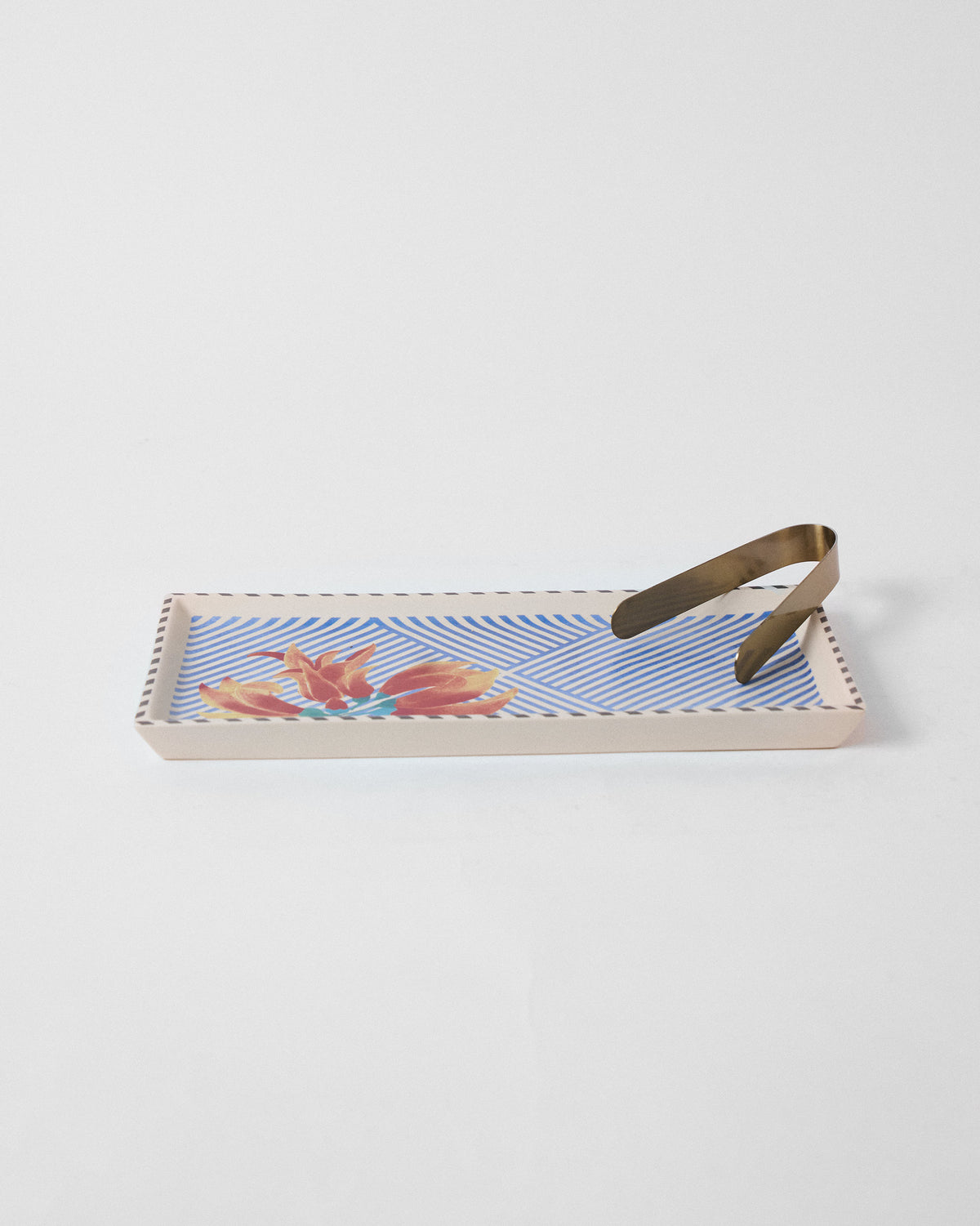 Palash cookie tray with blue stripes and orange flower print, brass tongs on top.
