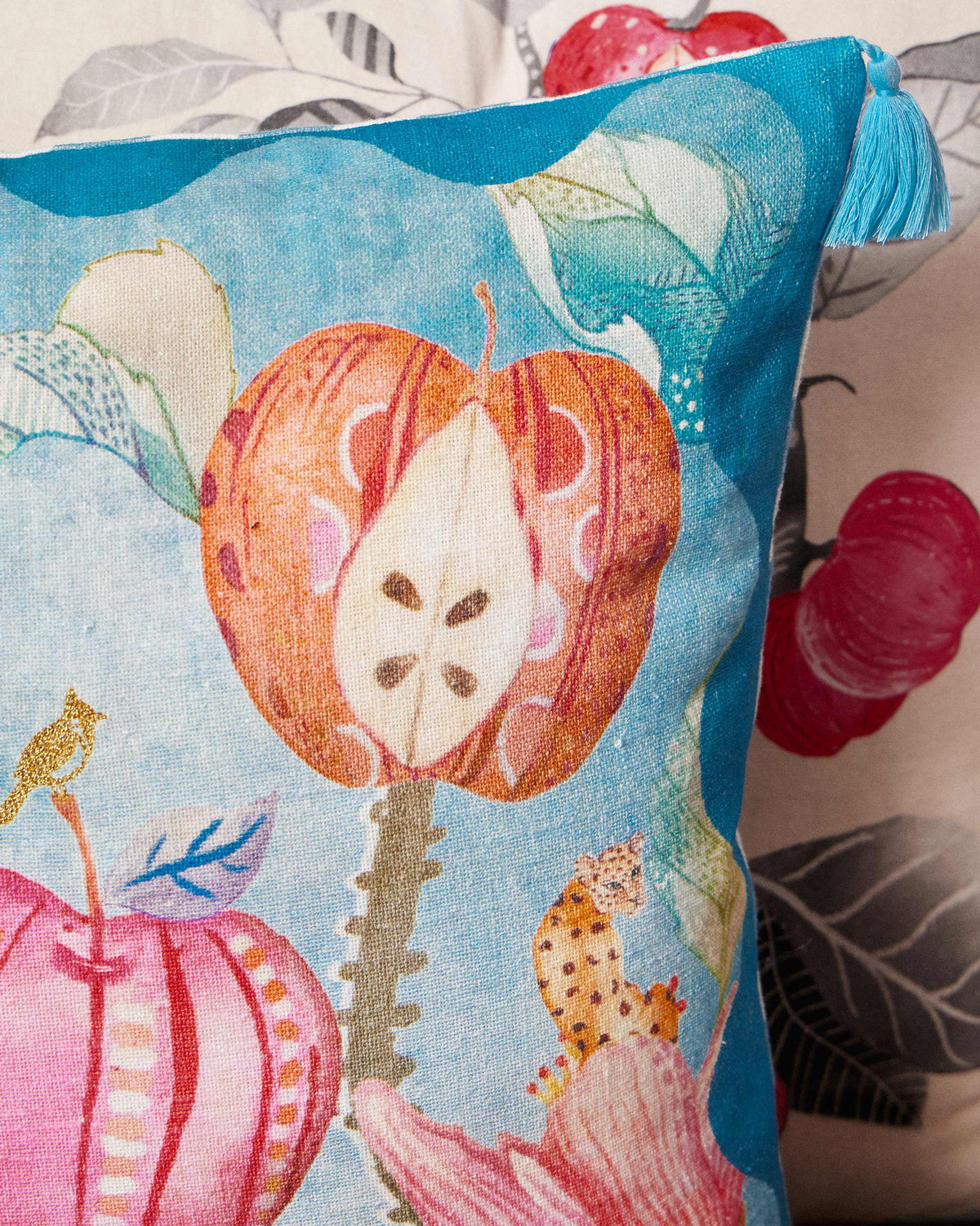 Close-up of a Seb cushion cover with a halved apple print in orange.