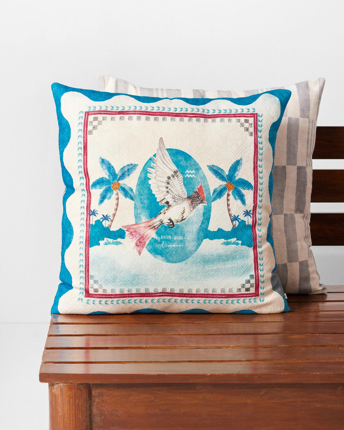 Blue Scallop cushion cover with a bird and palm trees on a blue scalloped border.