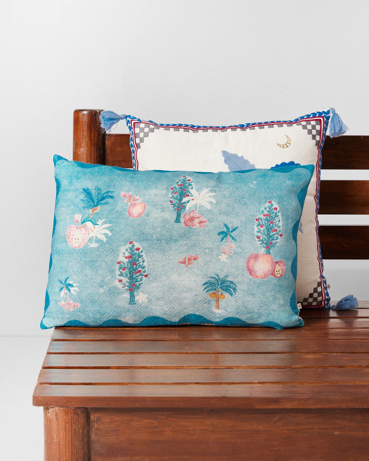 Aaranya cushion cover in teal with small tree and fruit motifs.