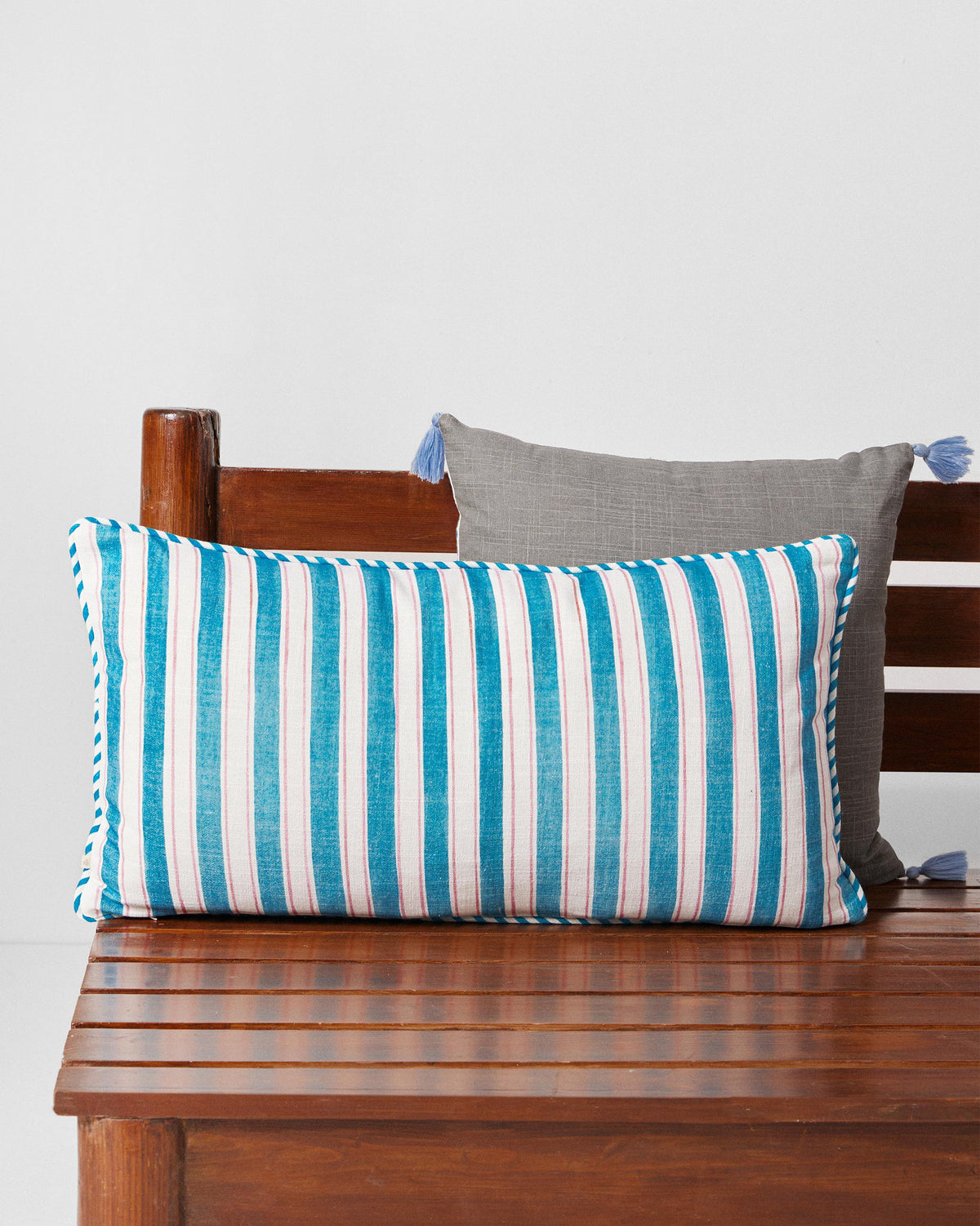 Sindhuraa cushion cover with blue and white vertical stripes and blue piping.