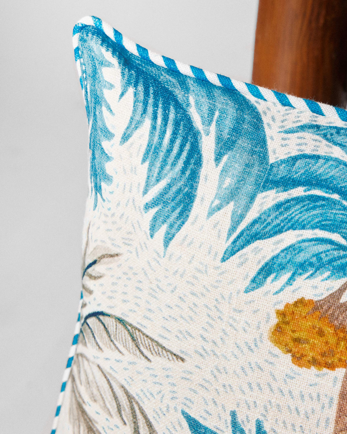 Close-up of a Sindhuraa cushion cover corner with blue piping.