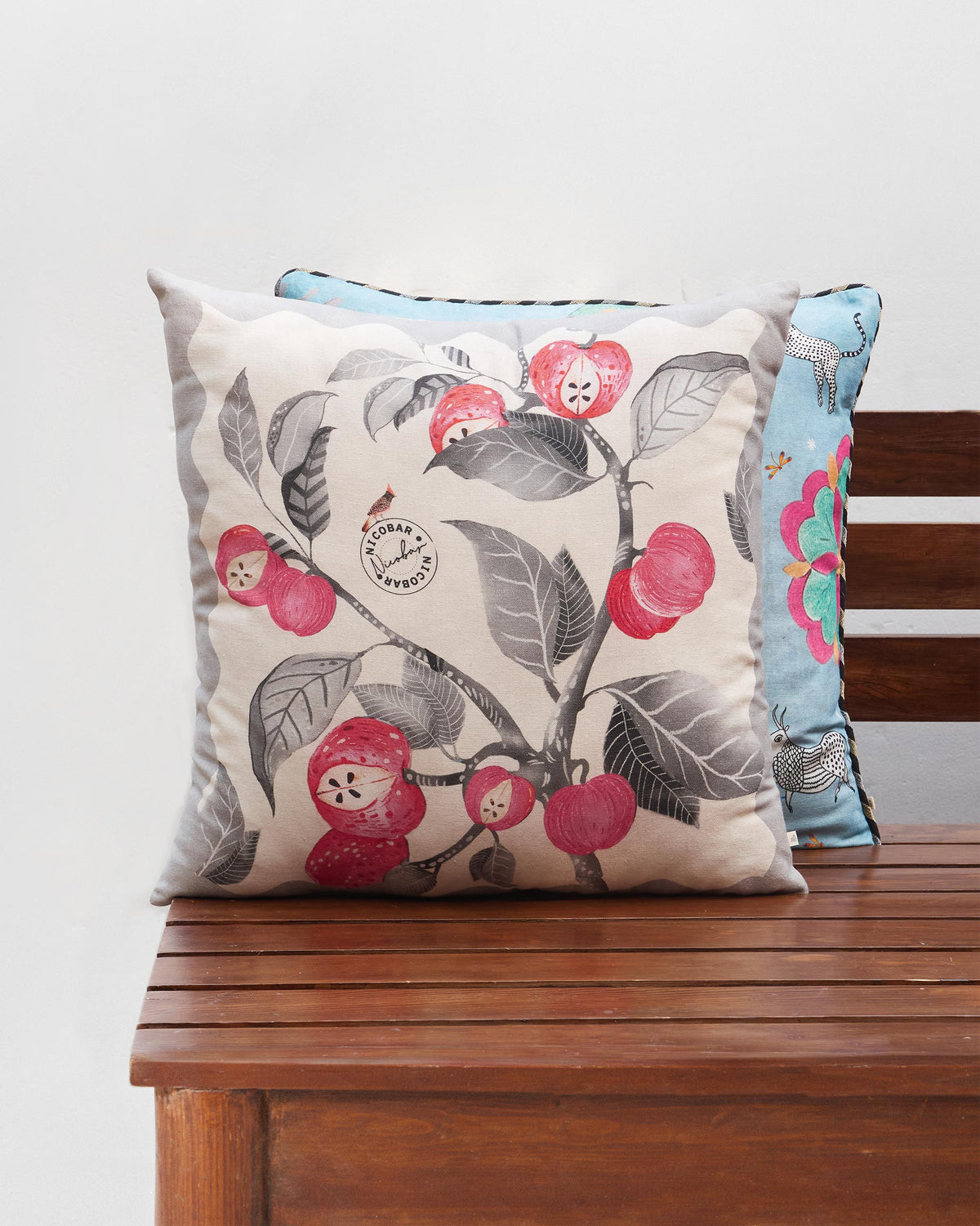 Orchard cushion cover with red fruit and grey leaves on a branch.
