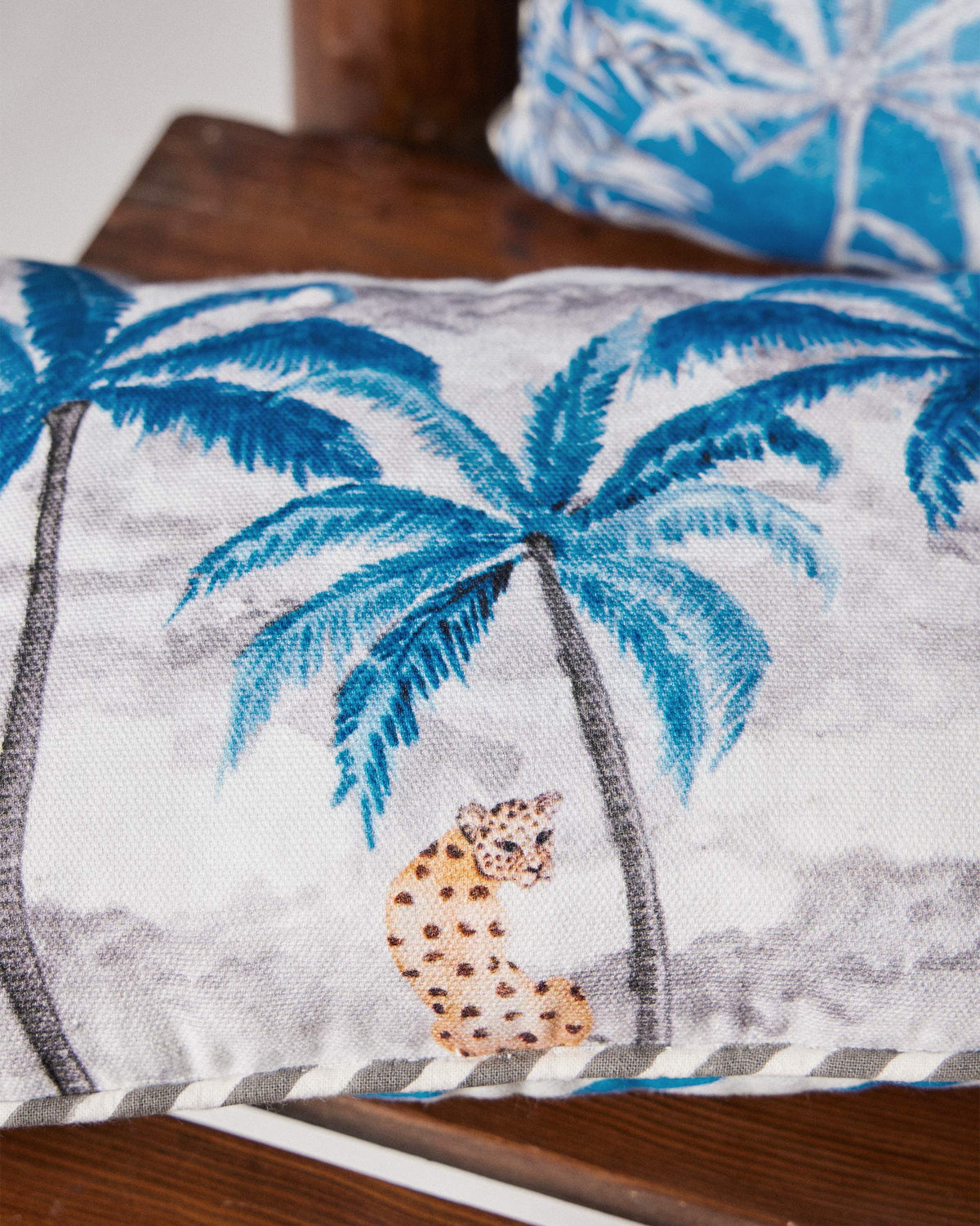 Close-up of a Sindhu car cushion with blue palm trees and a leopard.